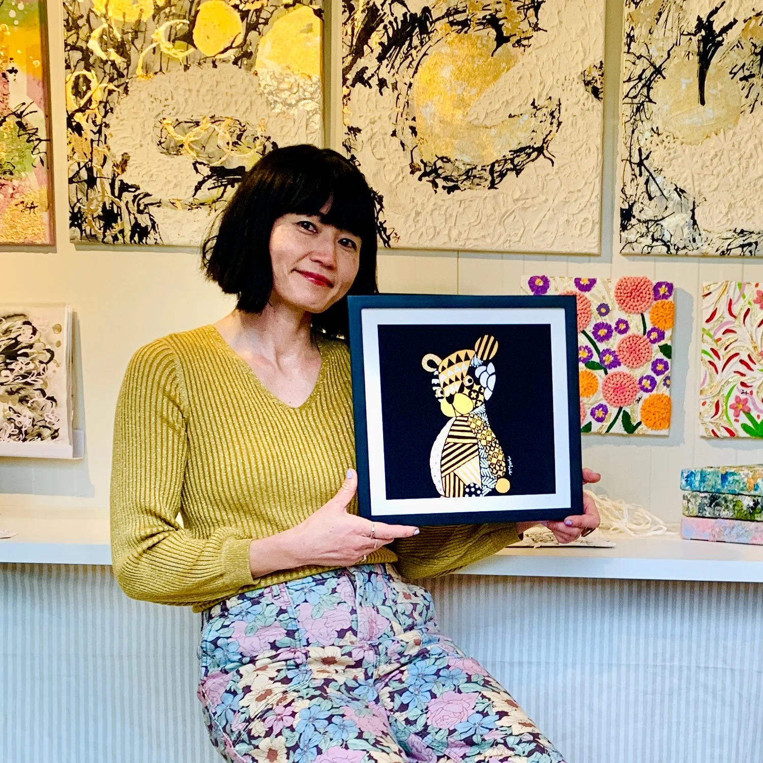 visual artist Yoshie Allan in her atelier, holding her artwork I Know Everything.