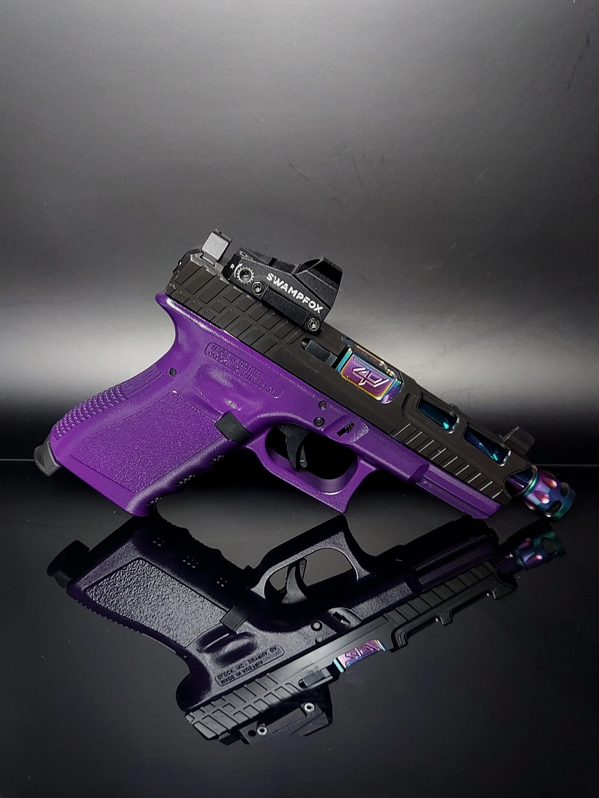 A purple and black handgun with a red dot sight on top, reflected on a glossy black surface.