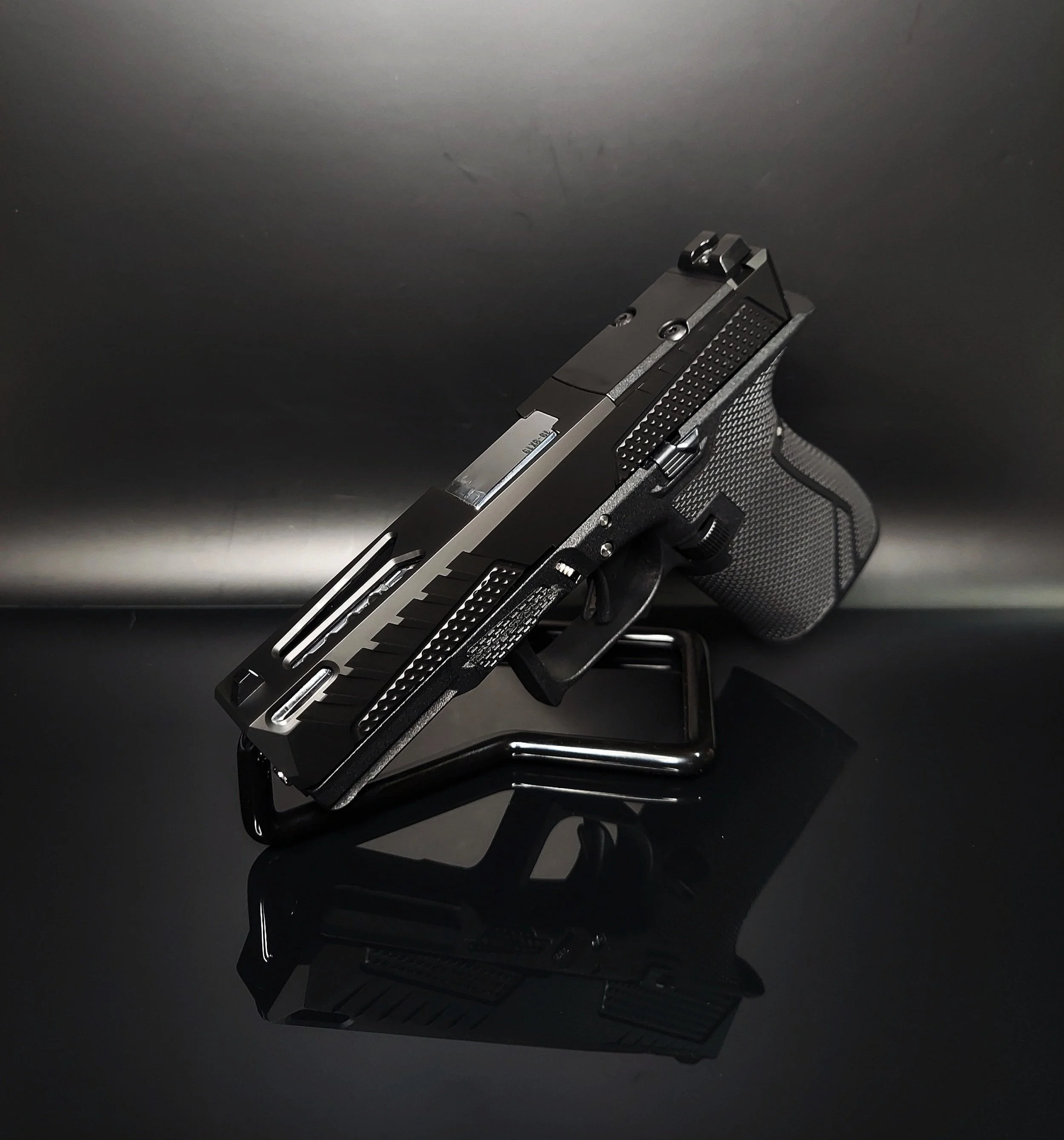 A black semi-automatic pistol displayed on a reflective black surface with a black background.