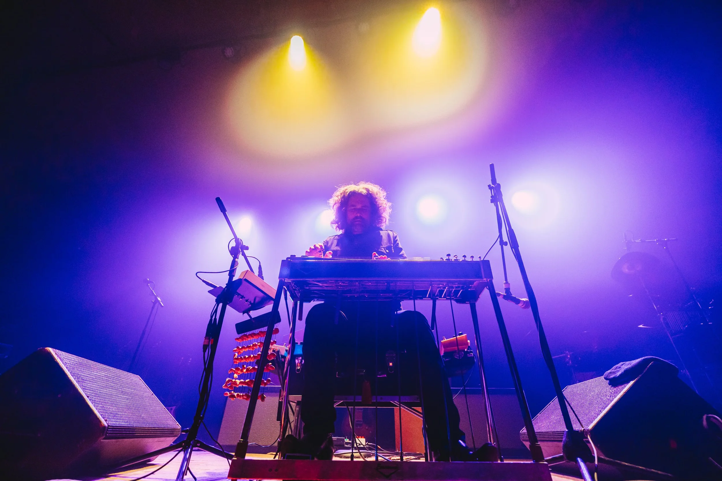 A musician with curly hair performing on stage in The Caverns in Pelham, TN.