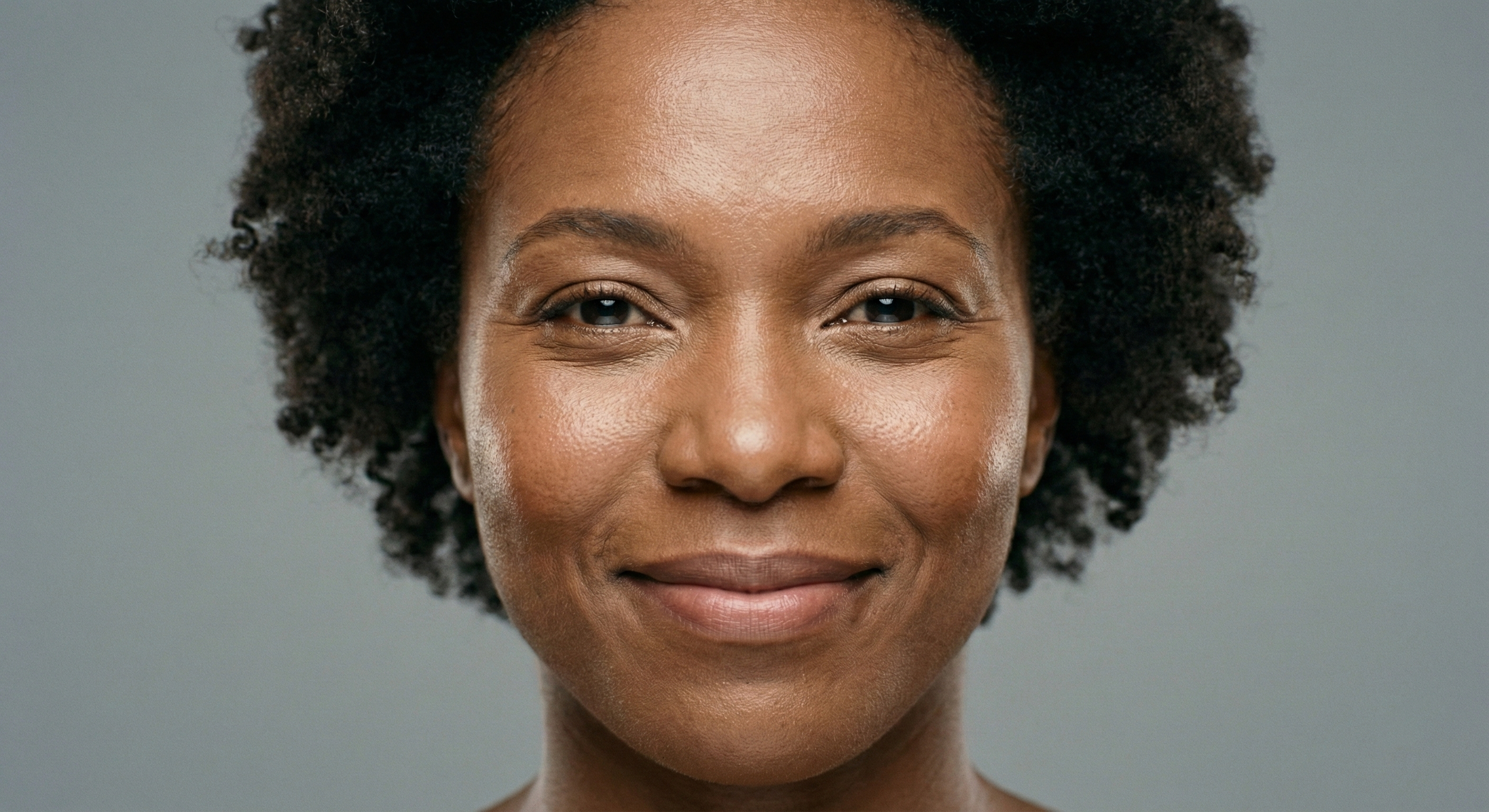 A close-up actor headshot of a Black woman with natural hair, clearly showing detailed skin texture and pores under beauty lighting to illustrate the 2026 anti-retouch casting trend in NYC.