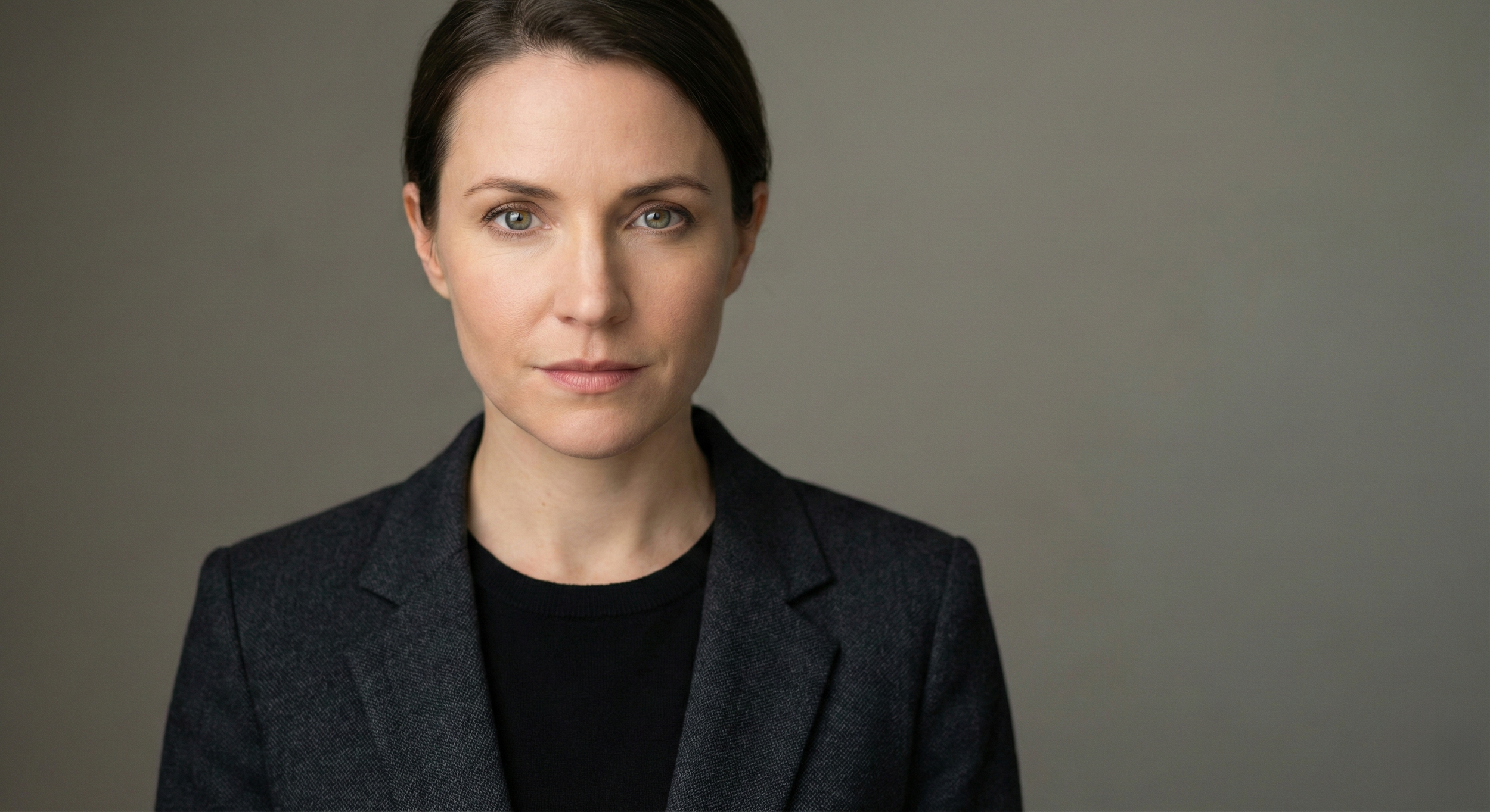 An actor headshot of a woman projecting intelligence and confidence in a simple dark blazer, illustrating the "vibe over type" casting trend for 2026.