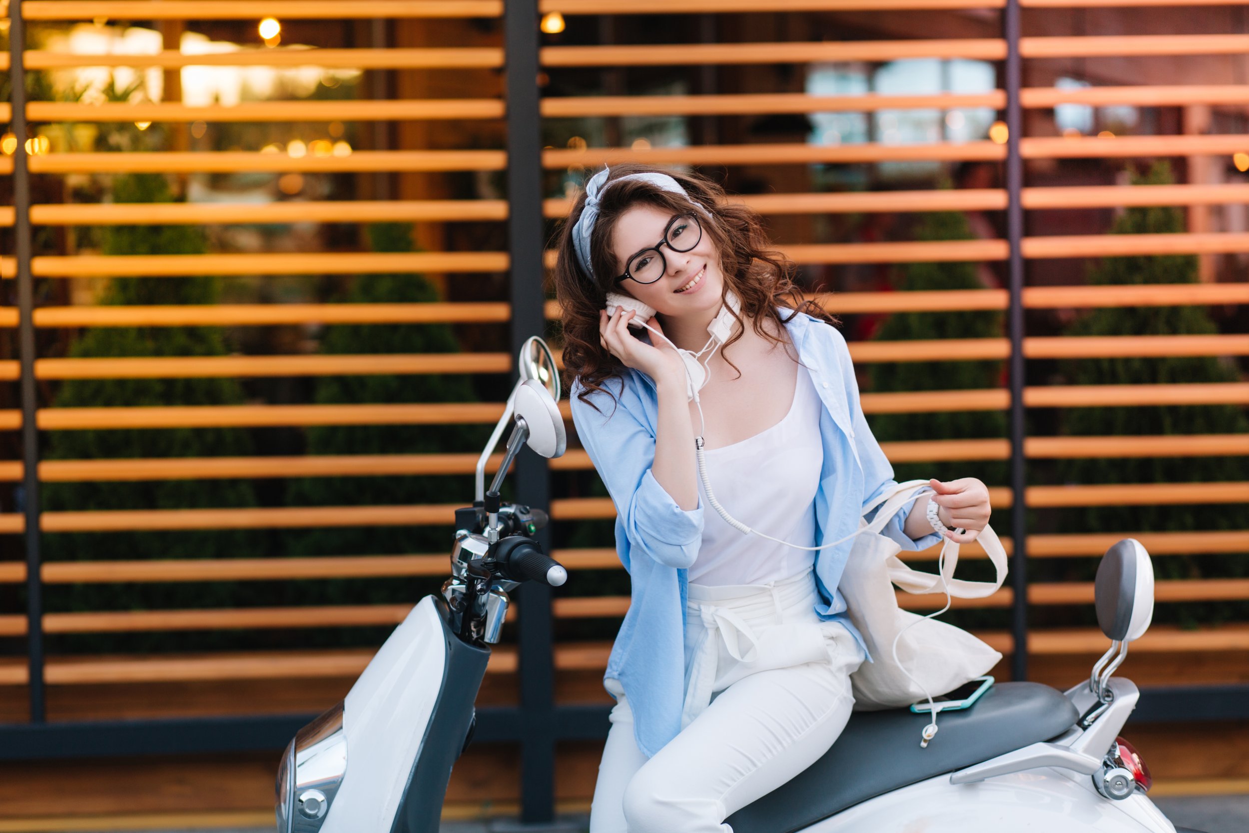 fascinating-young-lady-stylish-glasses-holding-white-eco-bag-listening-music-earphones-resting-after-shopping.jpg