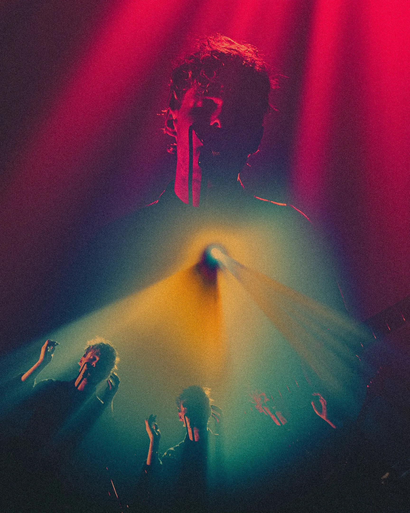 Une performance de groupe sur scène avec un grand écran derrière eux affichant la silhouette d'une personne, des lumières colorées et des faisceaux lumineux créant une ambiance dynamique.
