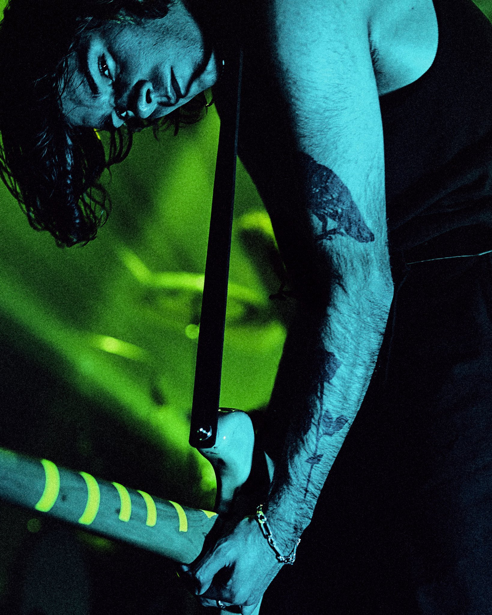 Une personne maniant un marteau sur un objet dans un environnement sombre avec une lumière verte diffuse.