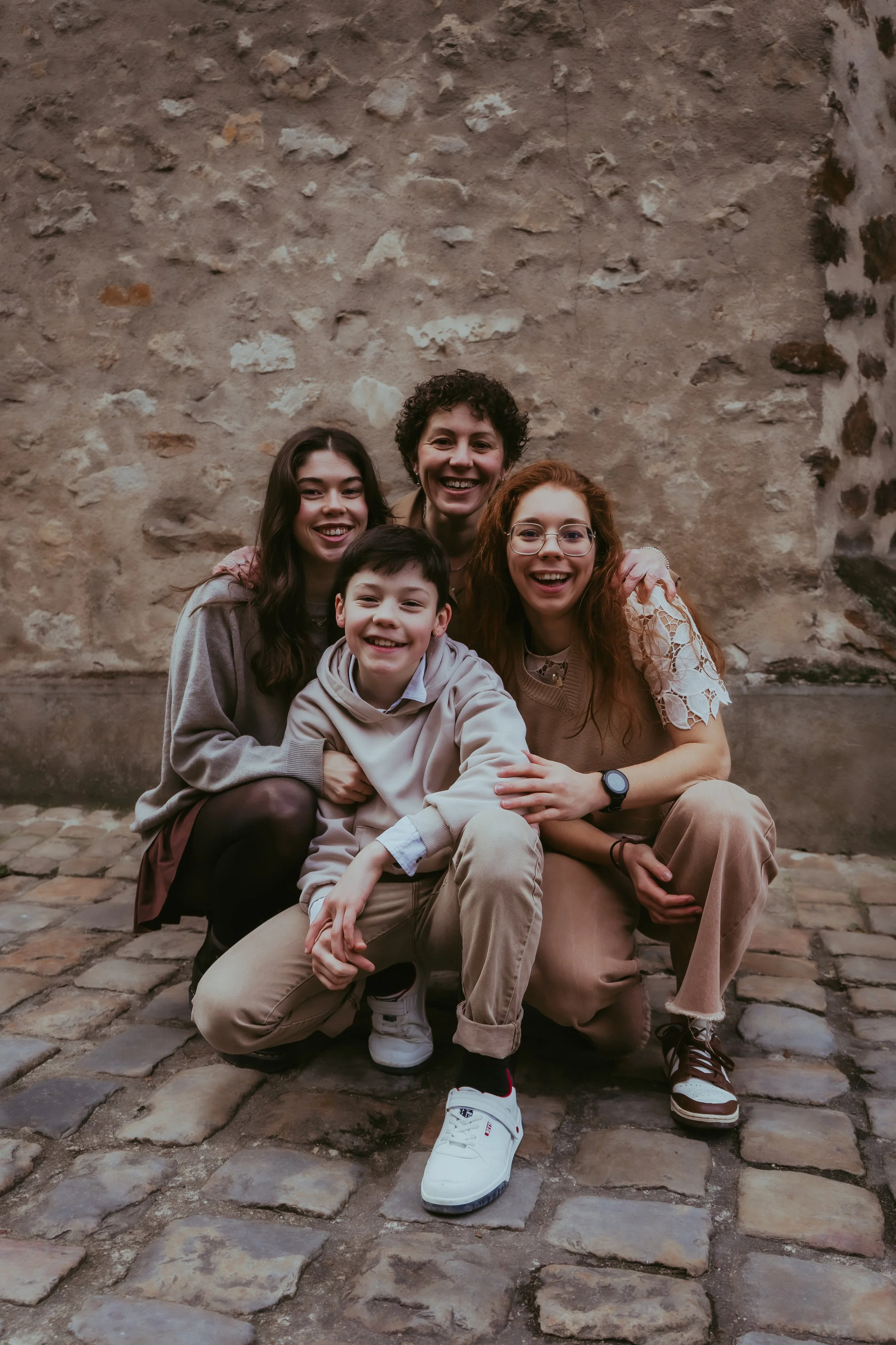 Groupe de cinq personnes souriantes devant un mur en pierre, posant pour une photo