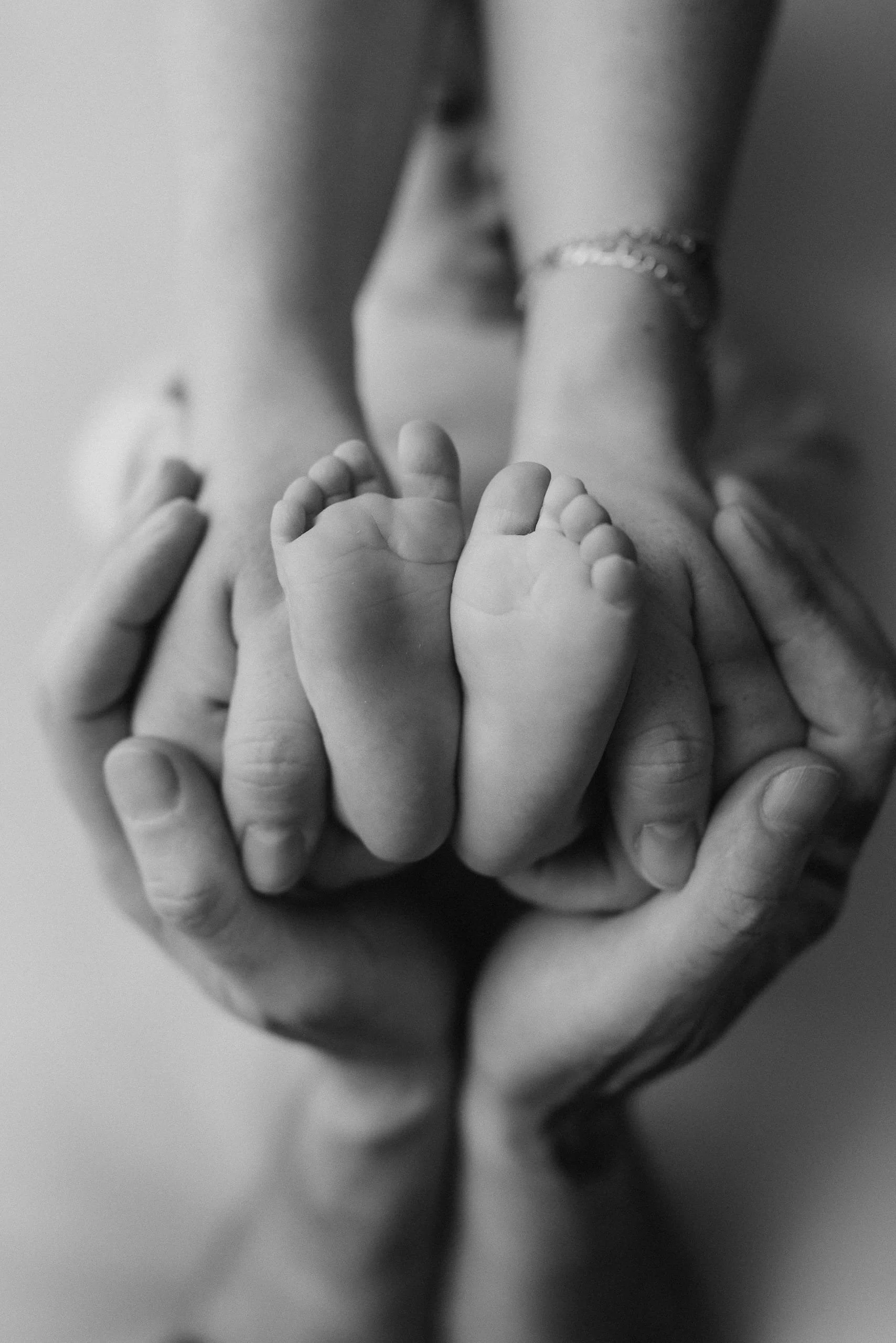 Schwarz-Weiß-Foto zeigt kleine Babyfüße, die in den Händen eines Erwachsenen liegen.
