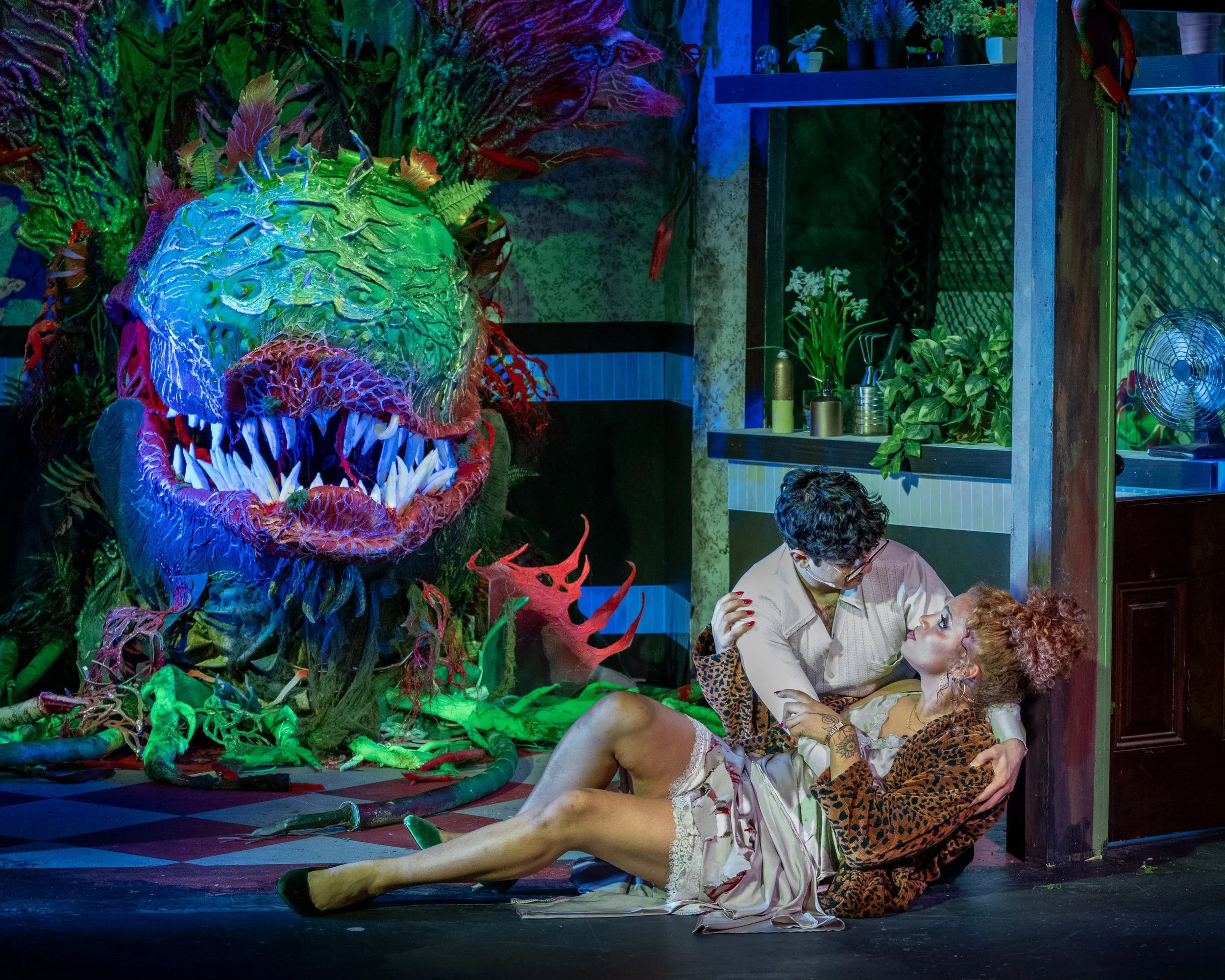Seymour cradles Audrey on the shop floor with the giant Audrey II puppet behind them in Little Shop of Horrors.