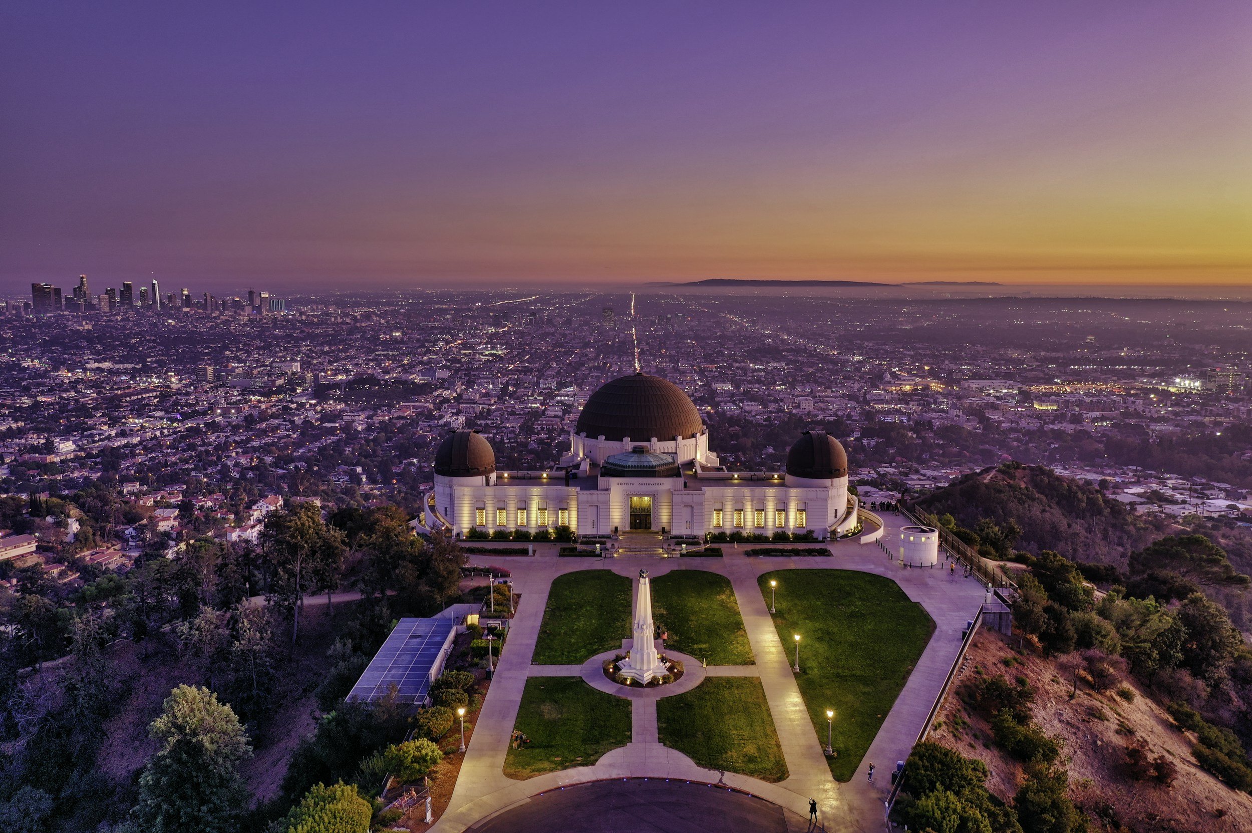 Pacific Ocean sunset over Griffith Observatory in Los Angeles with city skyline in the distance.