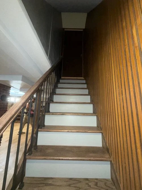 Renovated staircase with custom wood slat accent wall, stained wood treads, white risers, and new railing installed by P Jordan Construction in New Hampshire