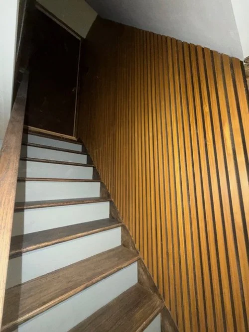 Staircase remodel featuring custom wood slat wall detail, refinished wood treads, and updated modern trim work by P Jordan Construction in New Hampshire