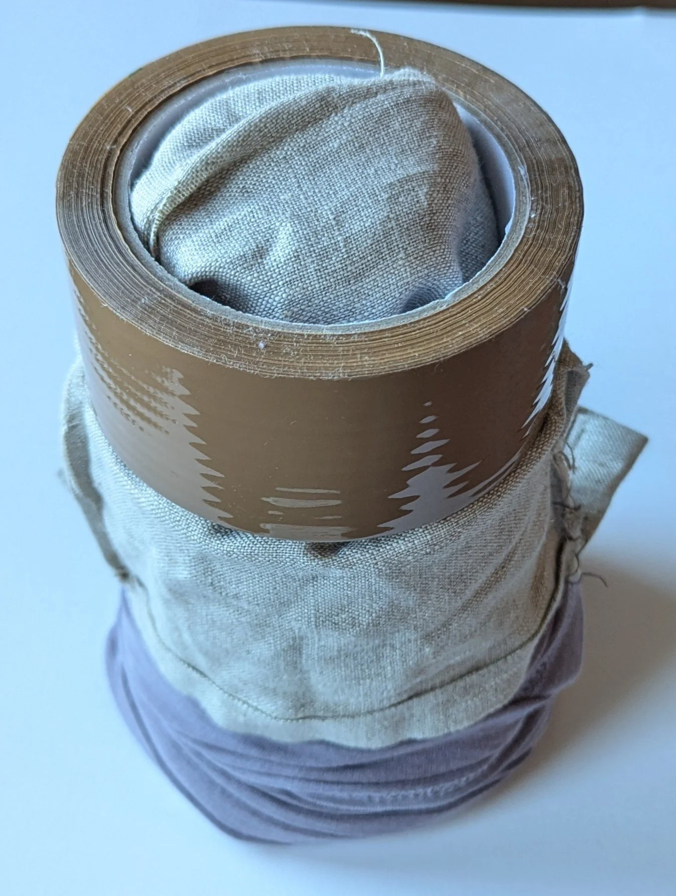 1L paint tin, 0.1L paint tin, t-shirt fabric, linen bag, parcel tape roll. 14 x 26 cm