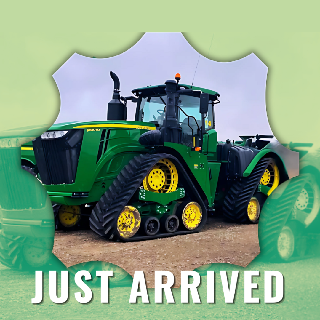 New green and yellow John Deere tractor with tracks and counters, seen through a torn paper frame, with the words "JUST ARRIVED" at the bottom.