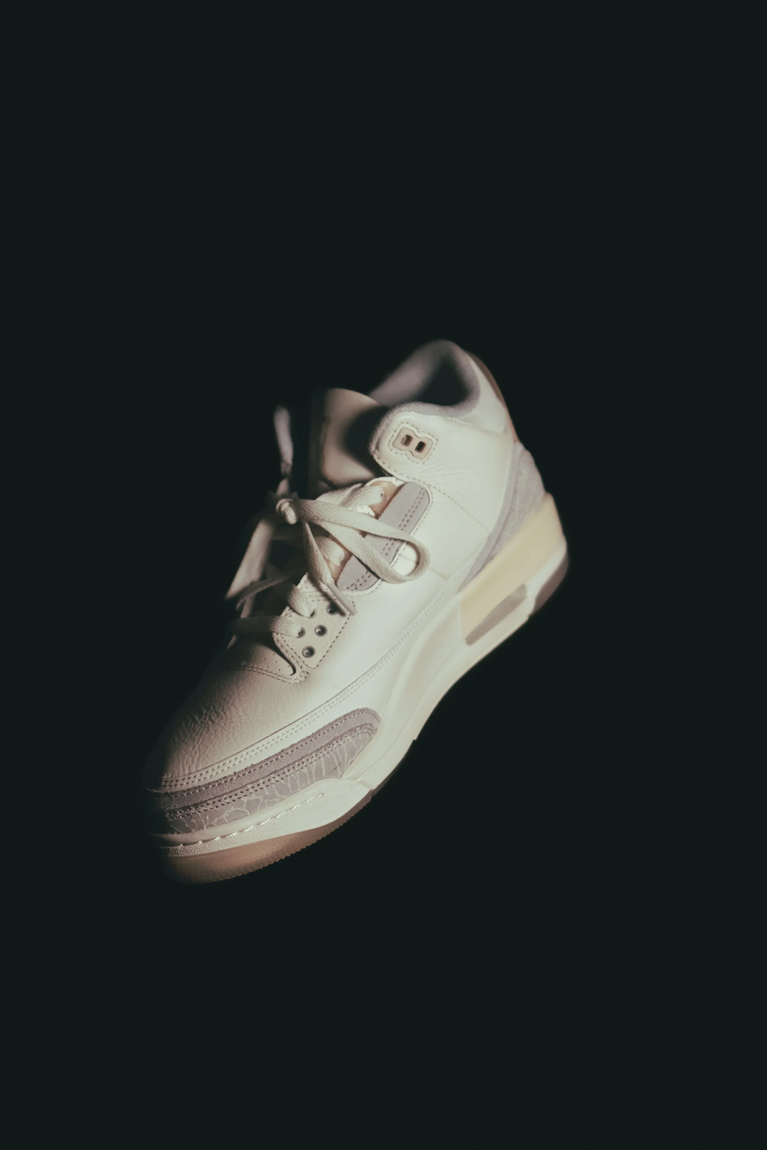 White sneaker with gray details on a dark background.