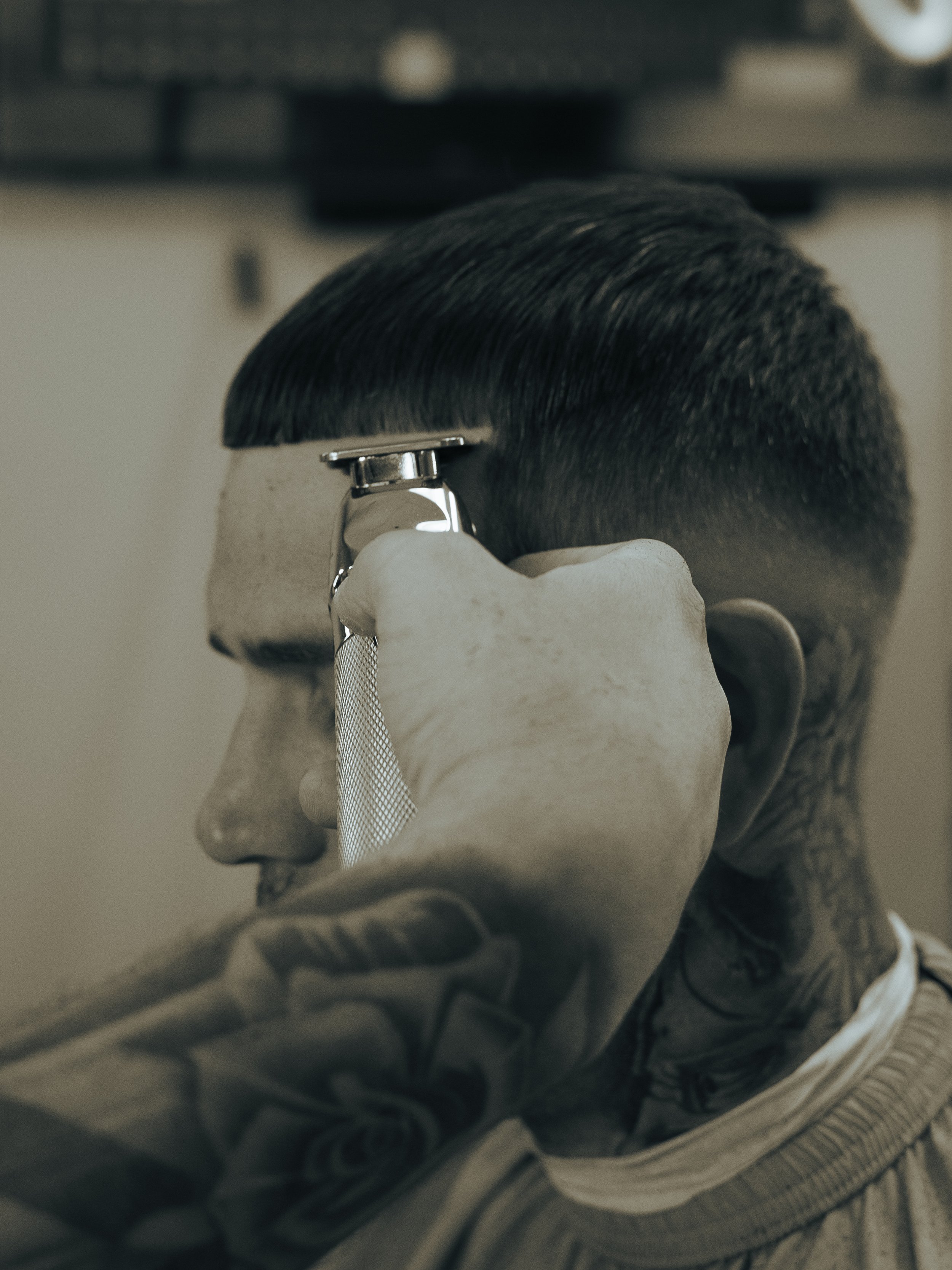 A man with tattoos receiving a close shave at a barbershop