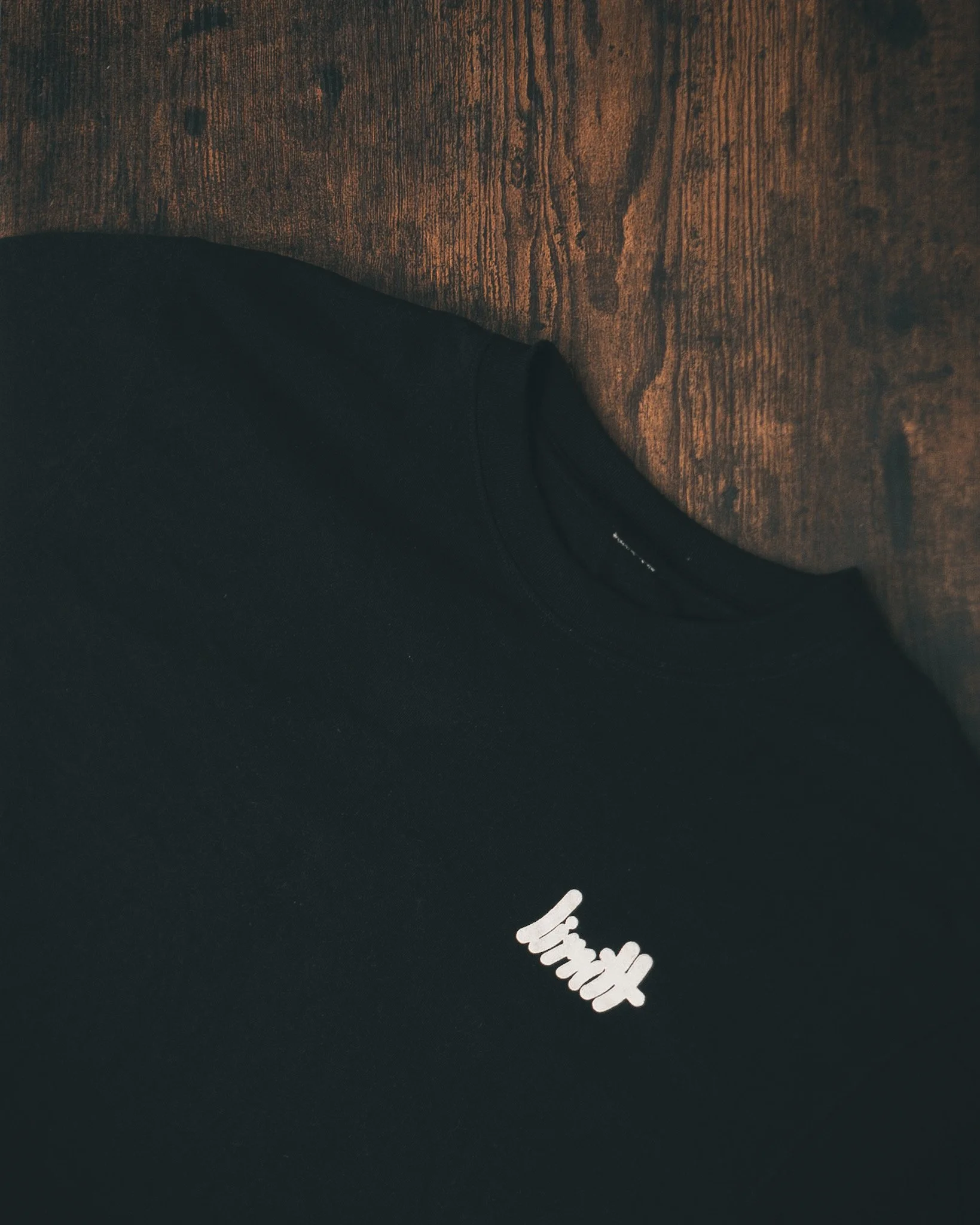 Black t-shirt with 'limit' text on wooden surface