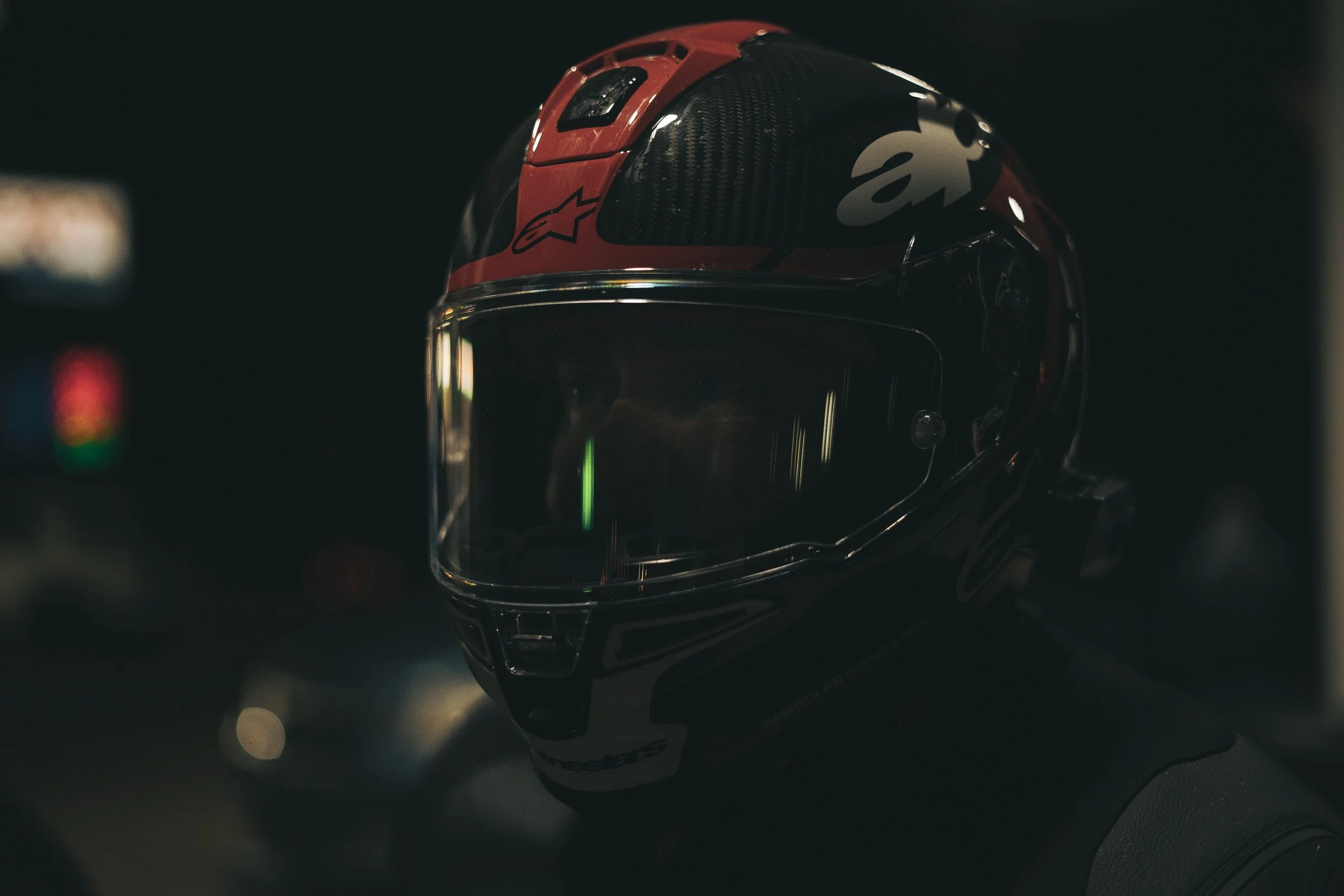 Close-up of person wearing a motorcycle helmet with a visor in dim lighting.