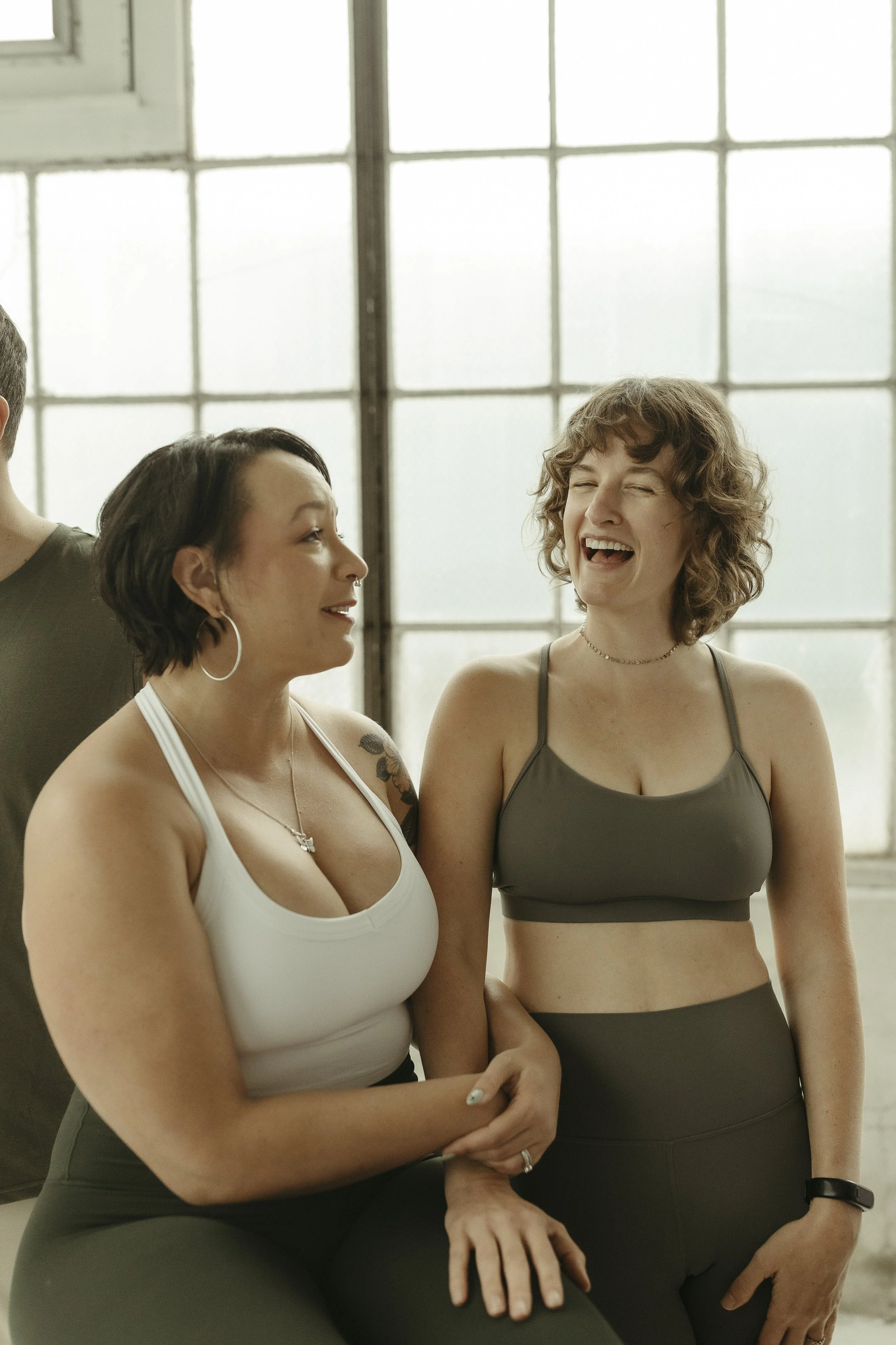 Group of people practicing yoga in a spacious studio with large industrial windows