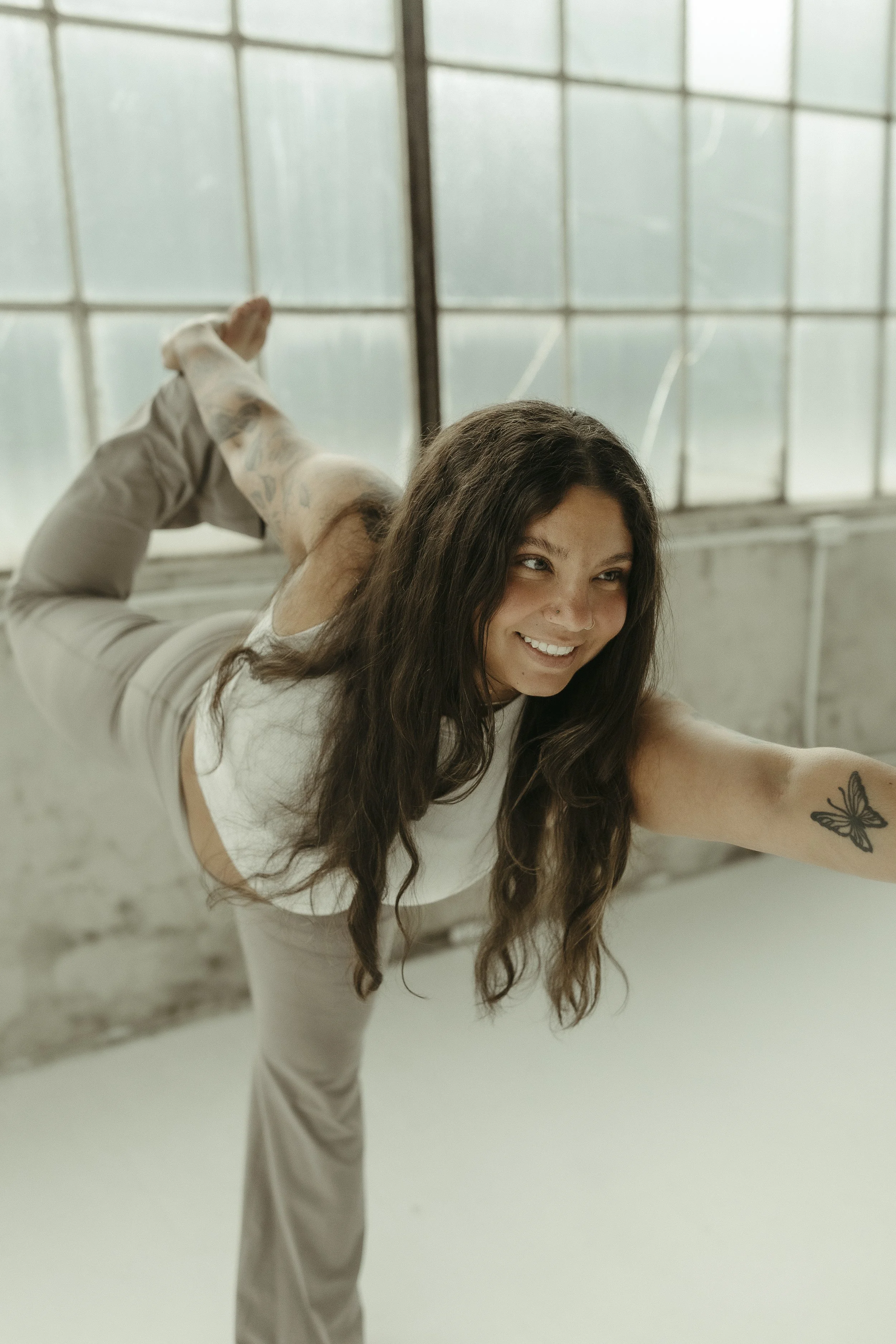 A man practicing yoga, performing a side angle pose in a bright, minimalistic room with a concrete floor and large window.