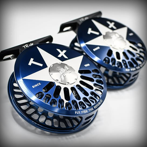 Close-up of two blue and silver fishing reel spools with a star design and the text 'Fly Fish the Republic' and 'Since' on them.