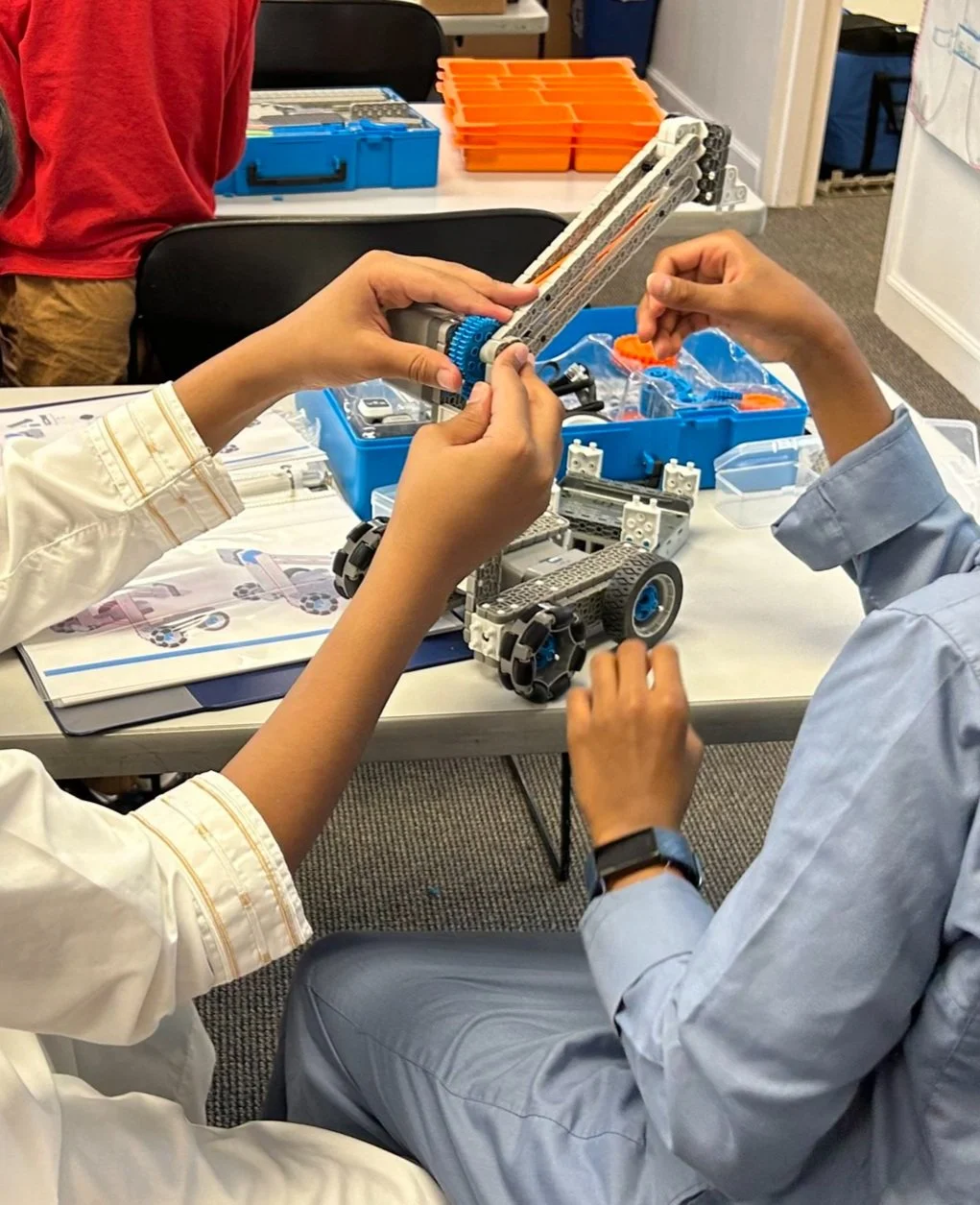 Students building a claw attachment for their robot during a robotics class