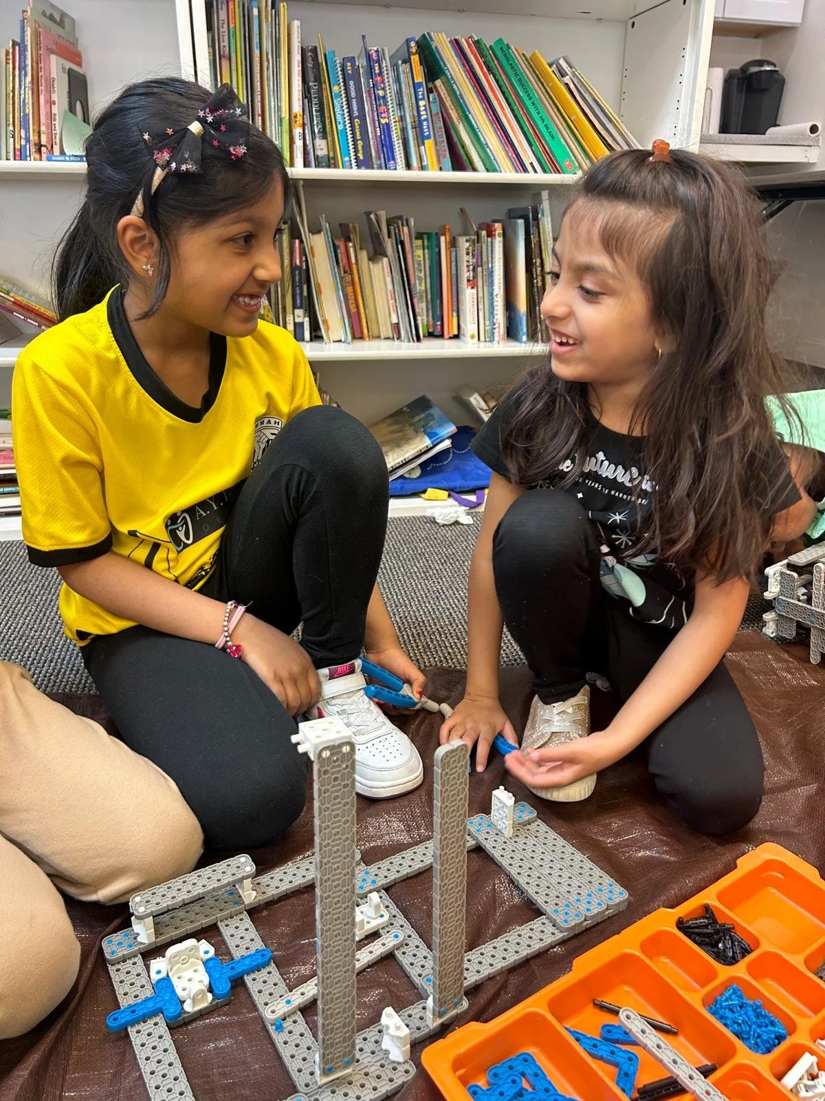 Young students smiling while building a house for their Mars rover during a STEM summer camp