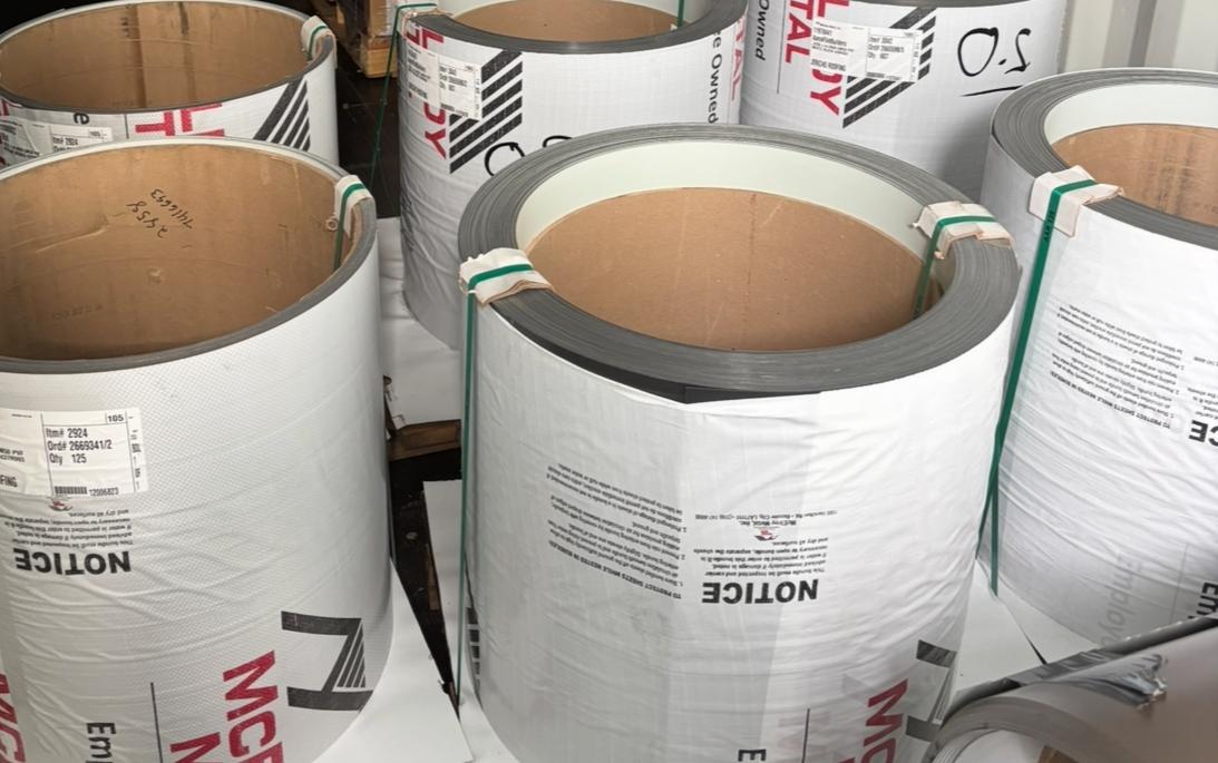 Large rolls of insulation material stacked on a surface, with some labeled 'NOCTE' and others with barcodes and product information.