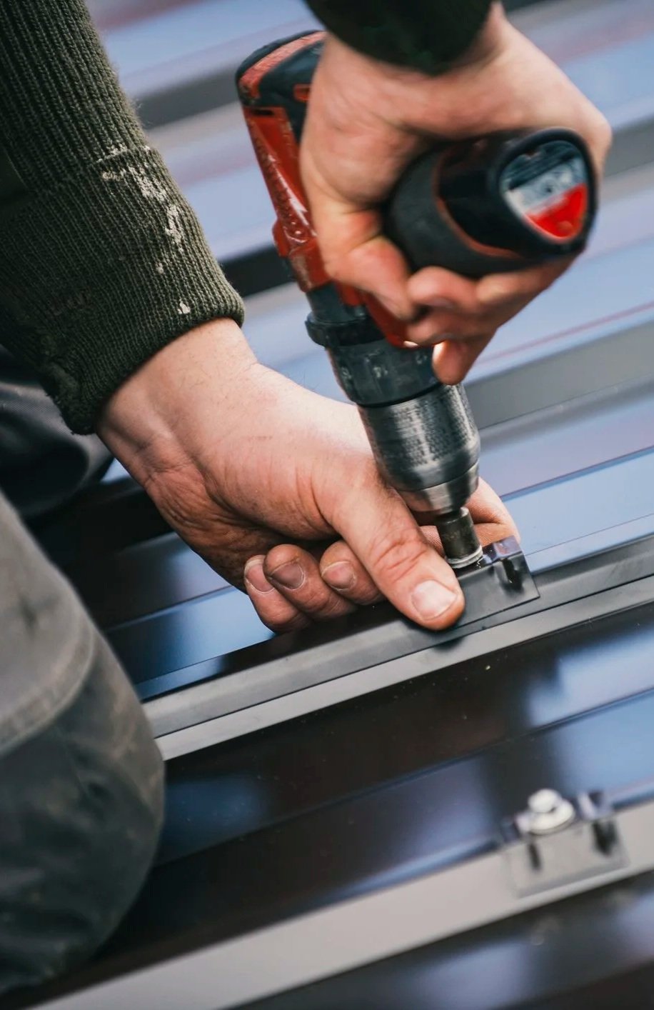 A person using a power drill to screw or drill into metal or a similar surface.