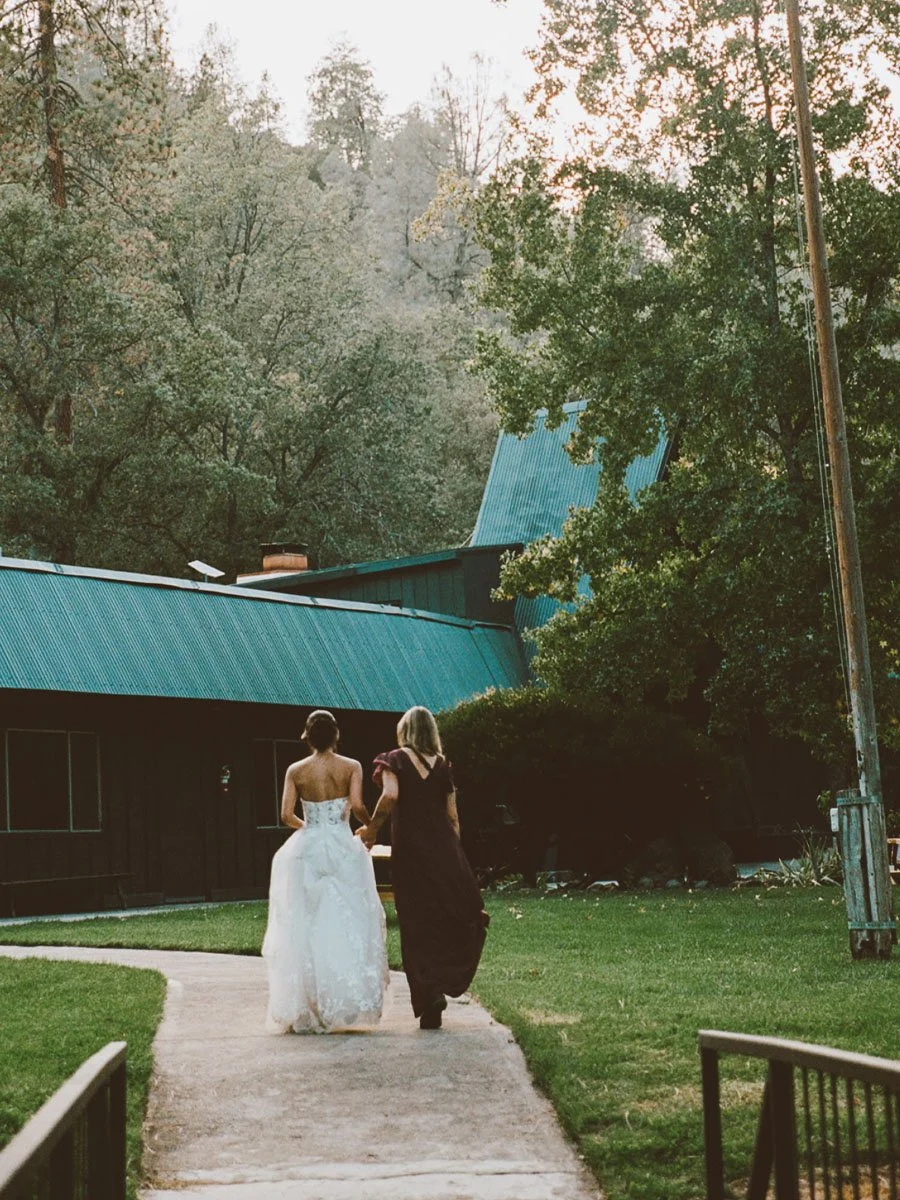 Bride and mother walking through front lawn area near Basecamp lodge at Deloro Valley