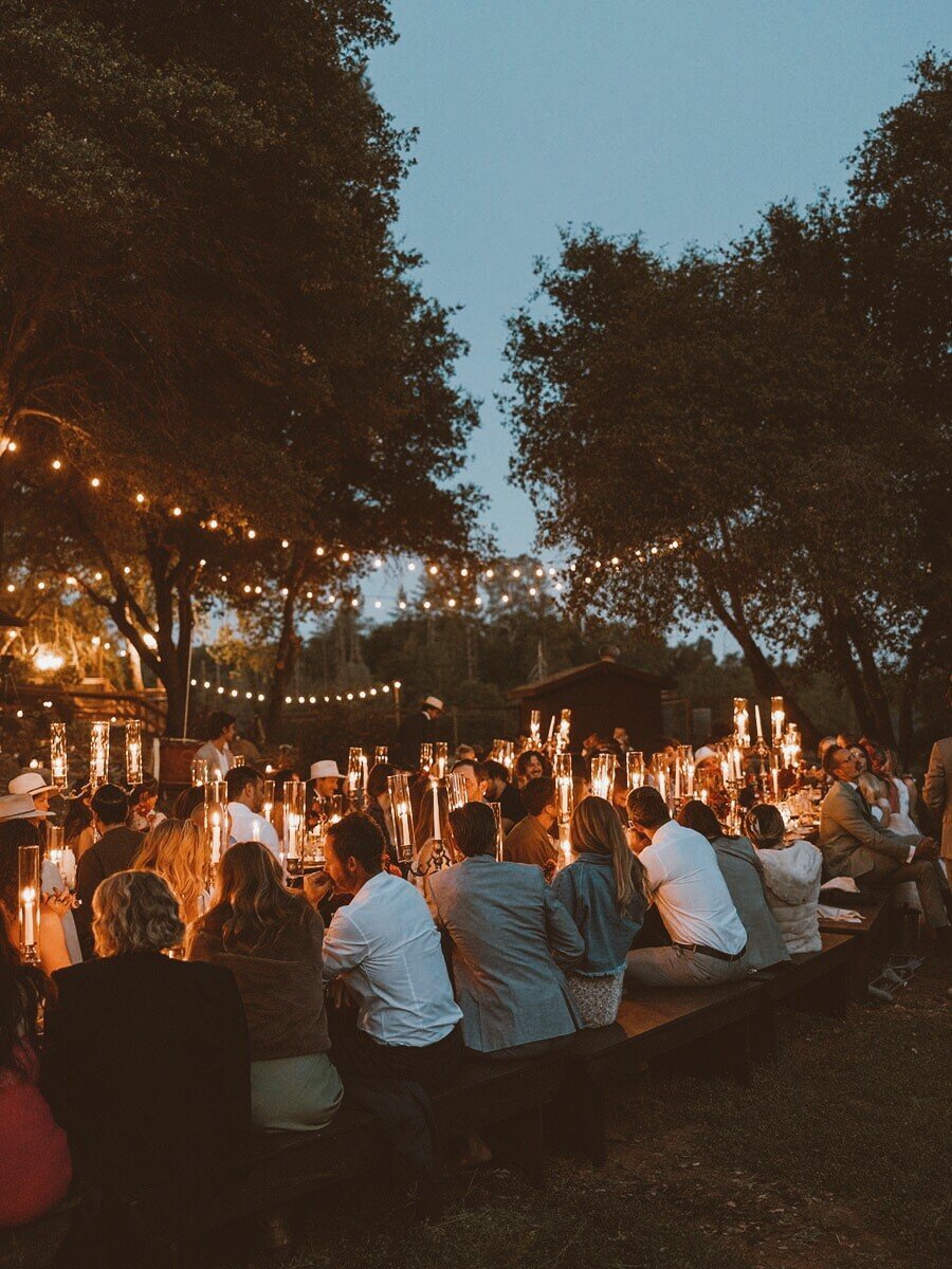Night time wedding dinner seating with candlelight and patio lights open air setting