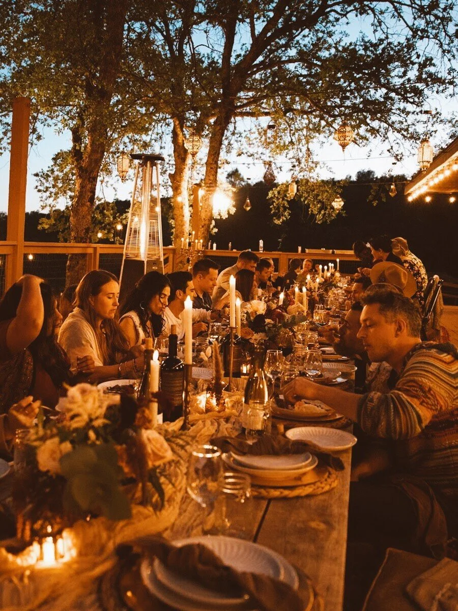 Wedding rehearsal dinner at dusk lit by chandeliers and candlelight on the deck at Upper Vista dining hall