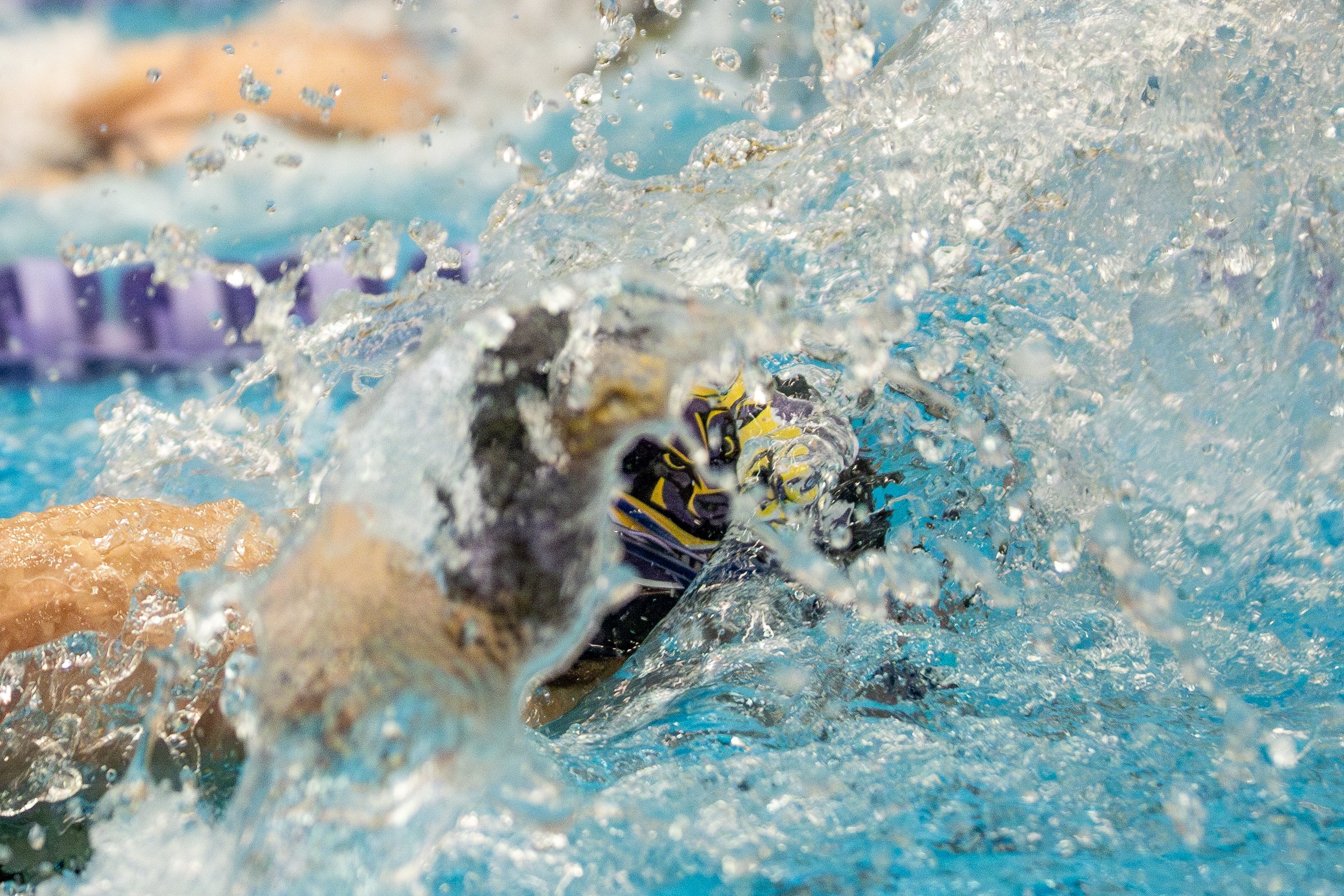 Swimmers competing in a swimming race, splashing water as they stroke through the pool.