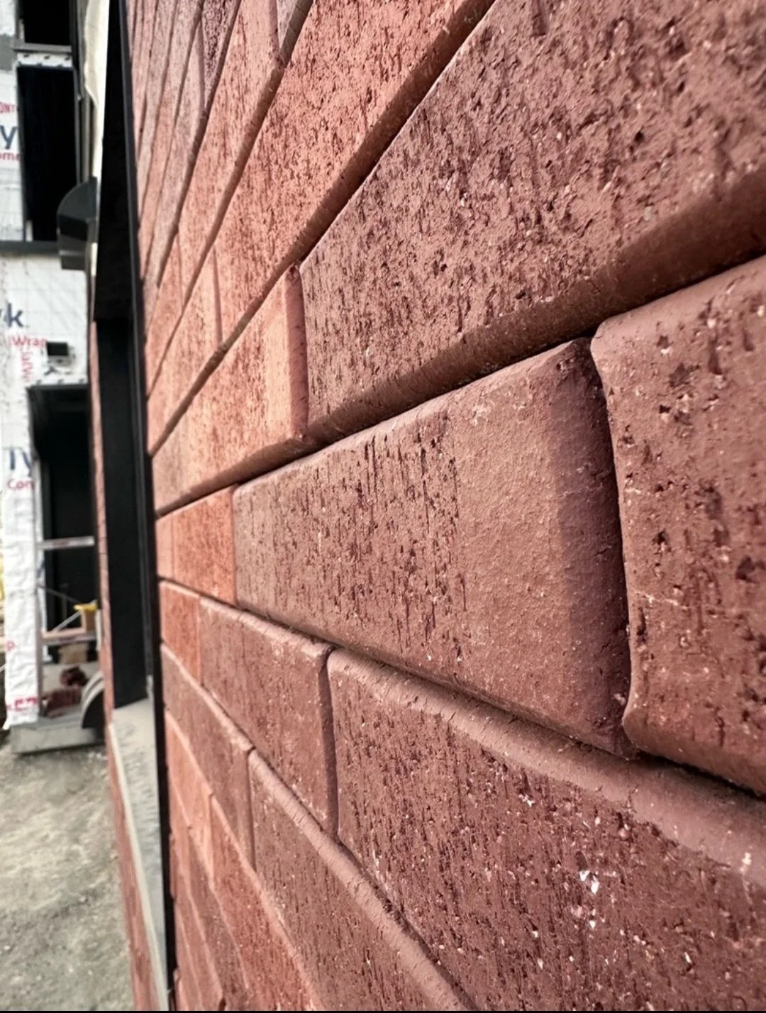 Close‑up view of installed exterior masonry units showing aligned courses, textured surface, and consistent joint spacing.