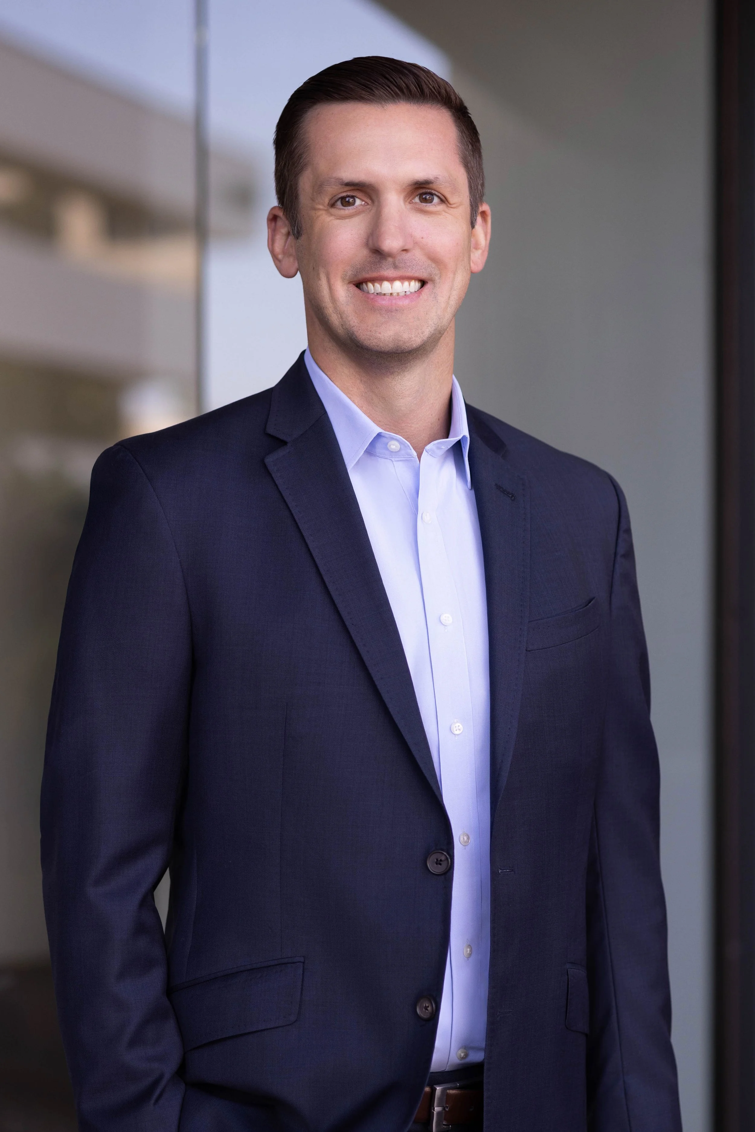 Business headshot of a financial advisor photographed outdoors near a Del Mar office building