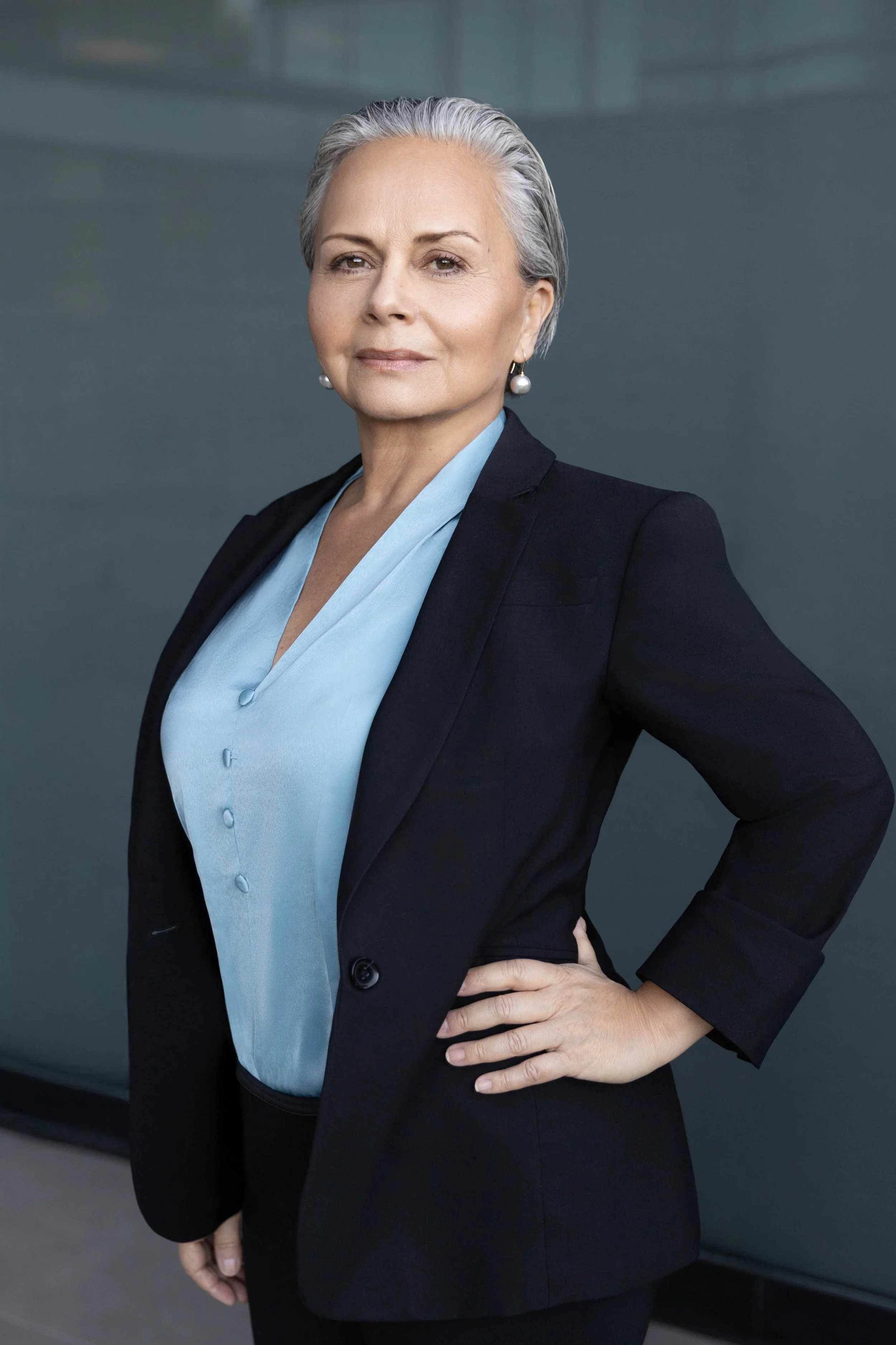 Confident professional woman posing outdoors in natural light wearing a blazer for a corporate headshot
