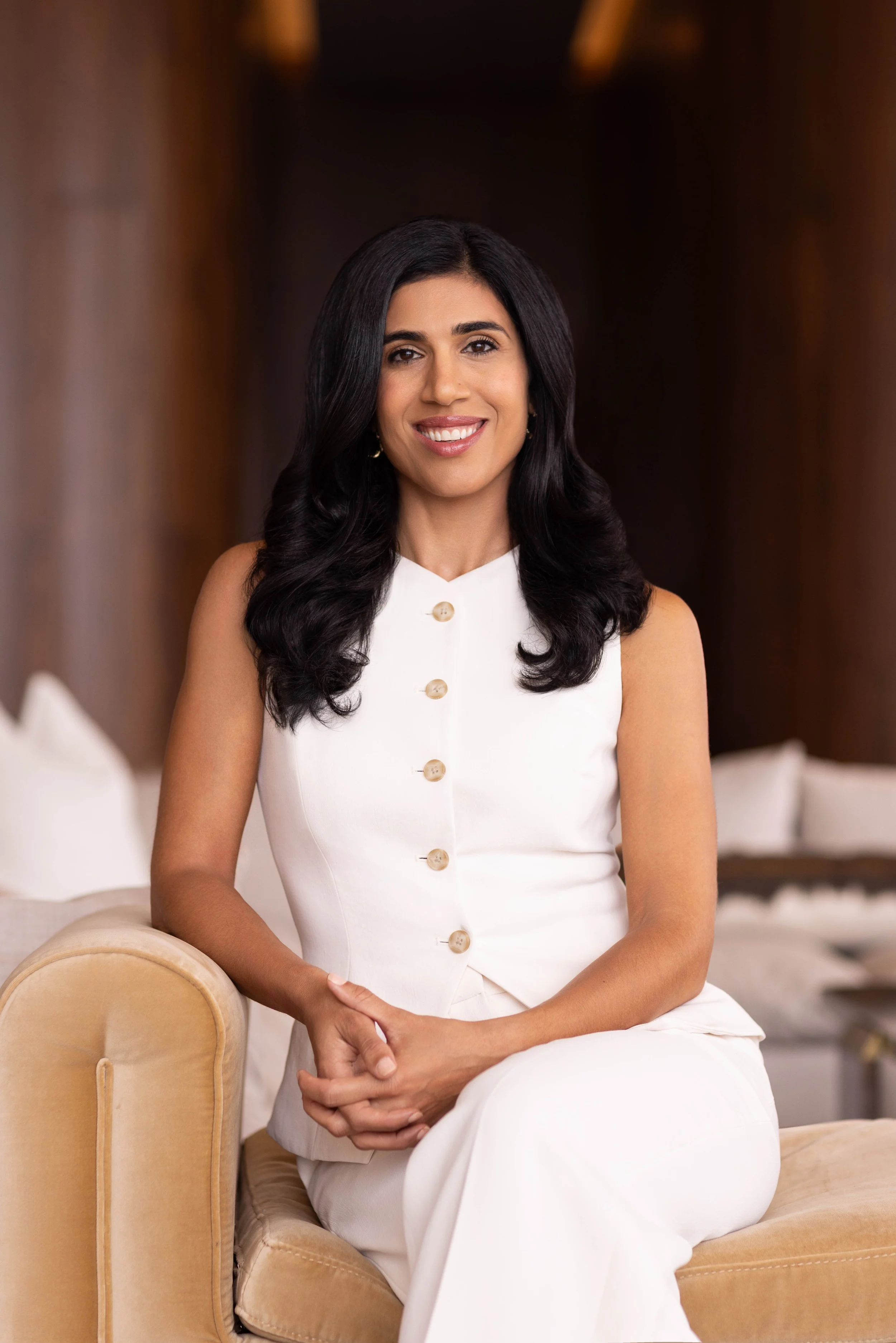 Professional brand headshot of a business executive seated in a modern office setting, photographed for personal branding and corporate marketing