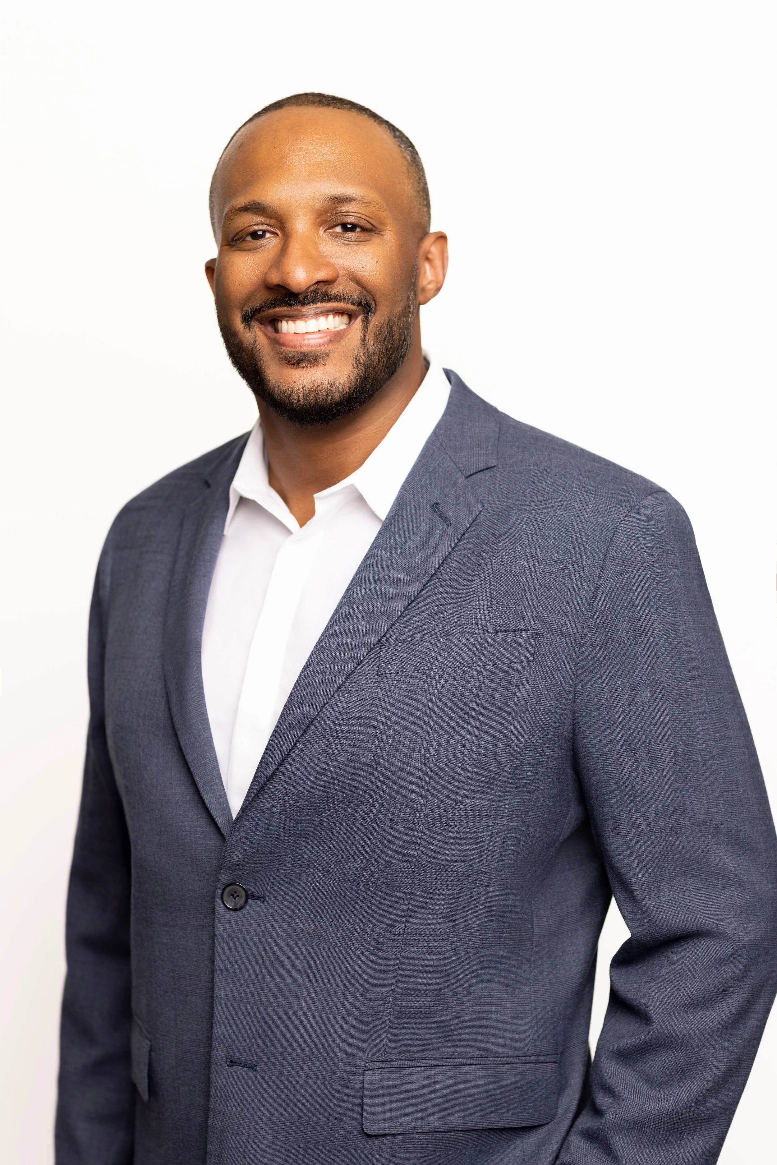 Professional in-studio headshot of a smiling businessman in a gray suit on a clean neutral background