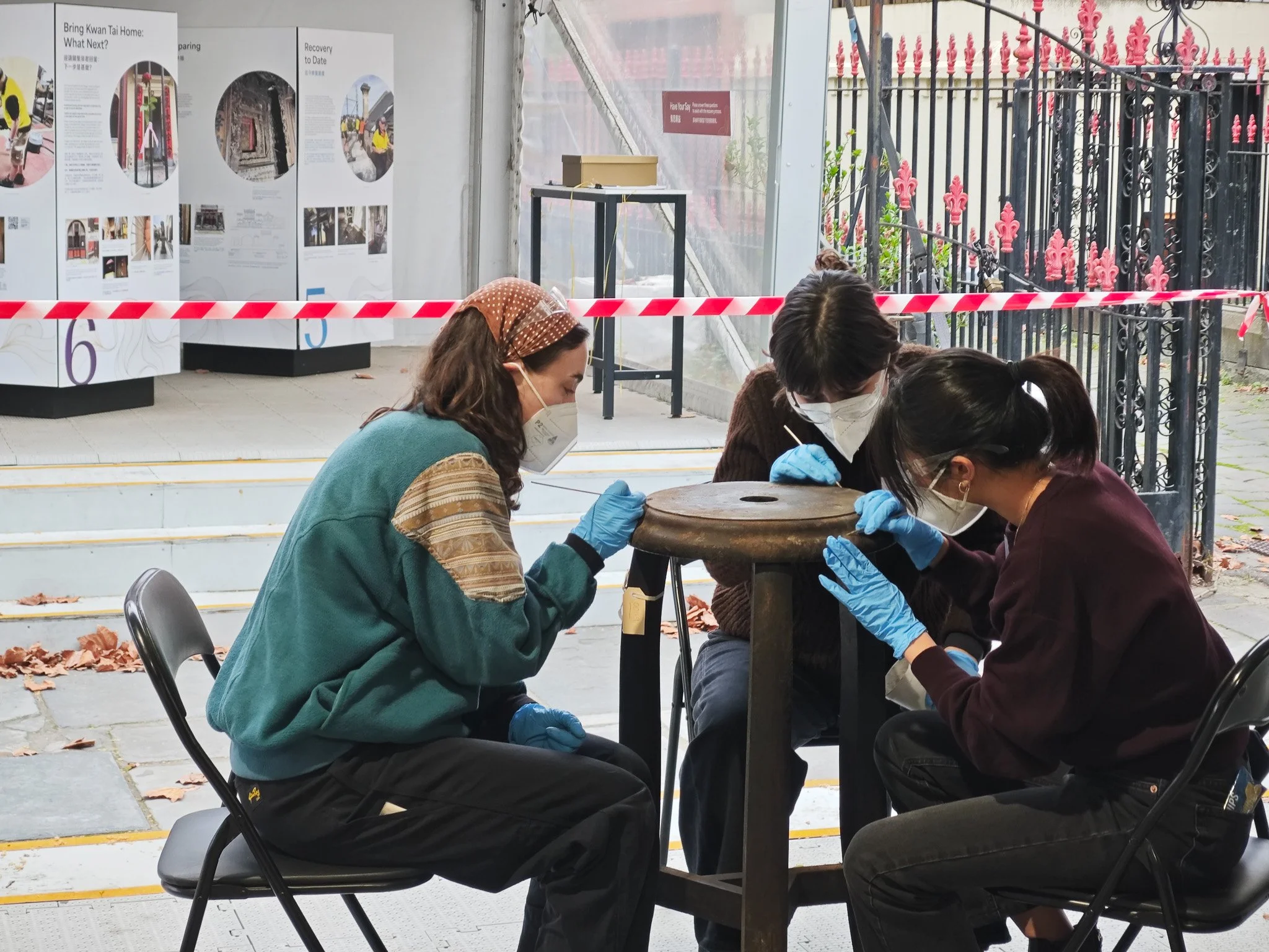  Volunteers using small brushes and bamboo sticks to carefully clean carved details on a temple object. Photo：Danni Lin 
