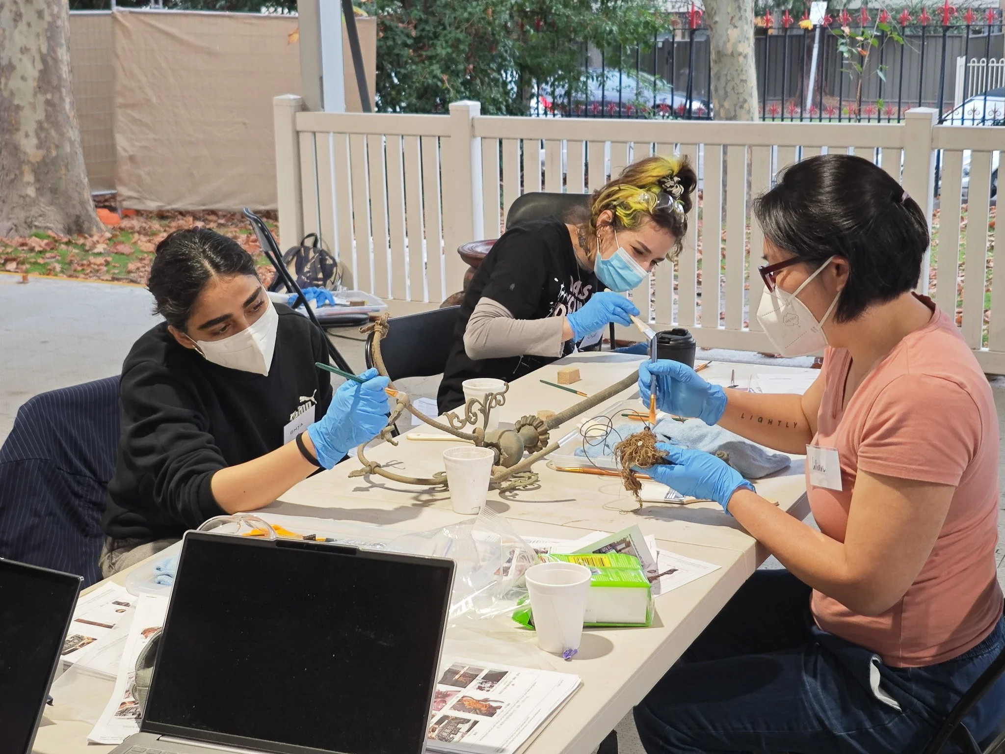  Volunteers using&nbsp; brushes and tools to clean detailed metalwork on a temple object. Photo：Danni Lin 