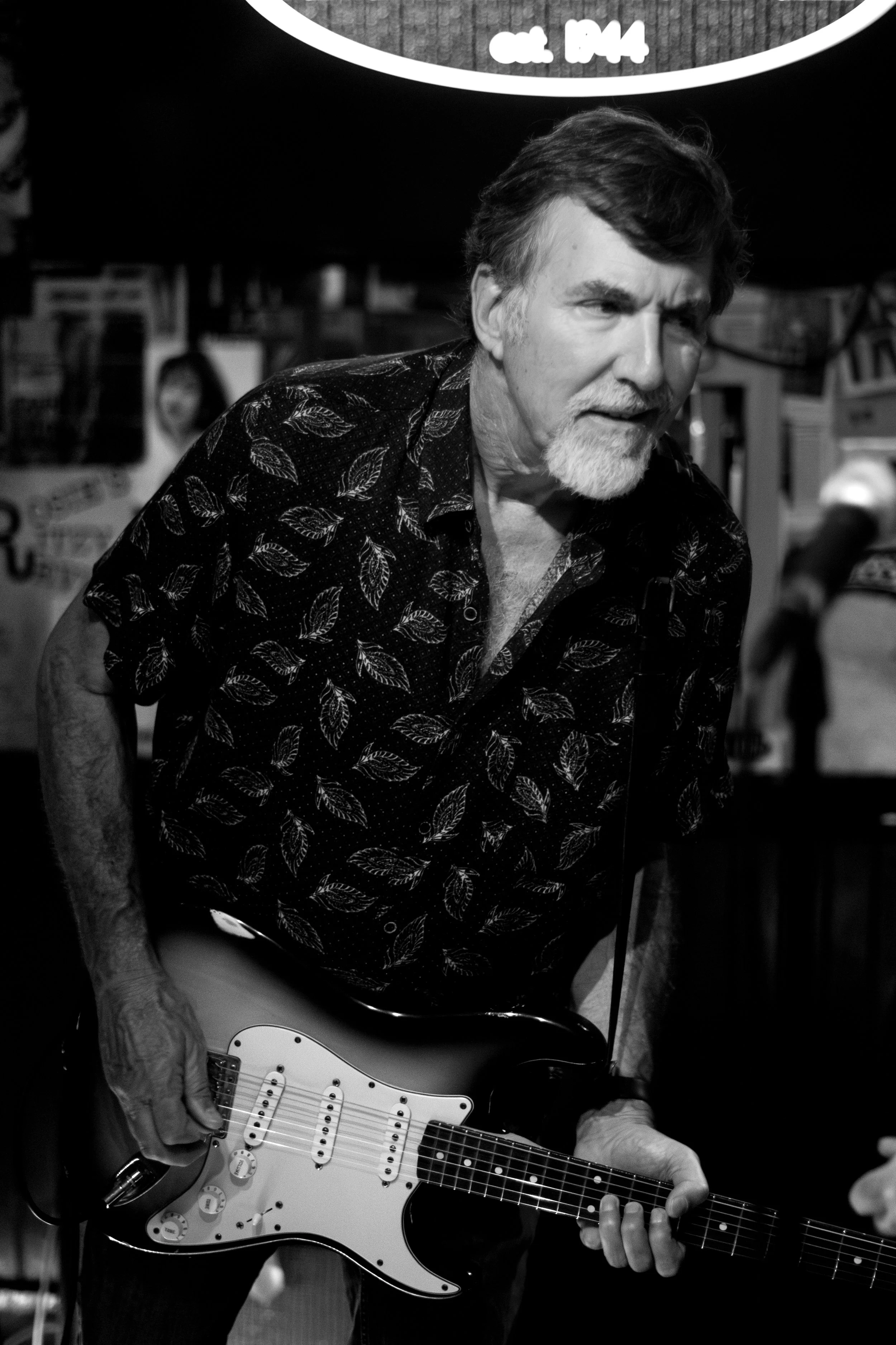 An older man with a white beard playing an electric guitar.