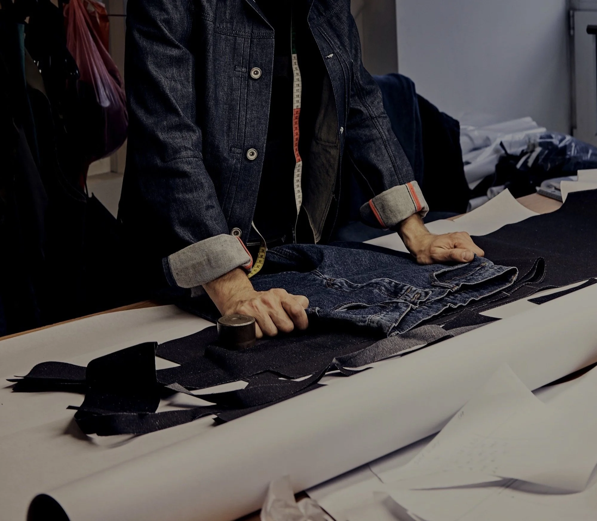 Person crafting denim clothing on a work table at Authent office.