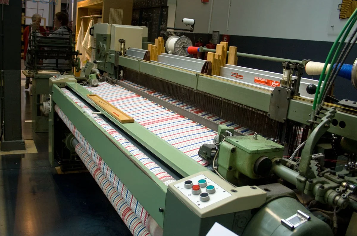 Industrial weaving loom with fabric in production in a textile factory.