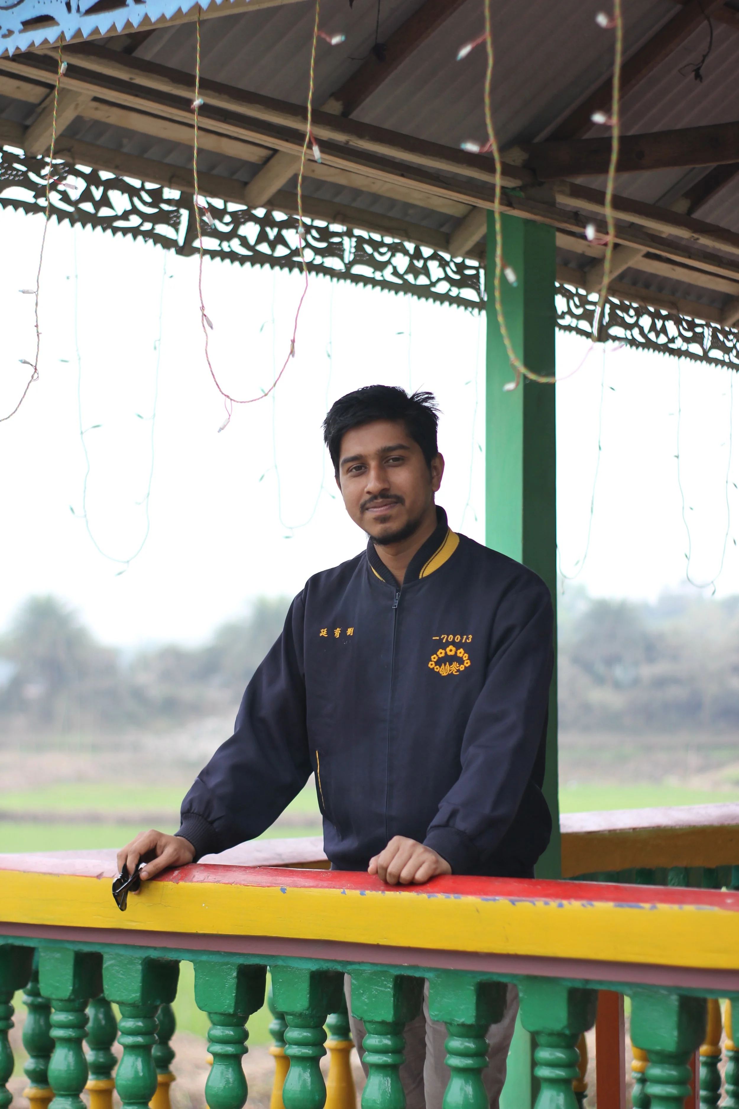 Man in a blue woven jacket (Waiter uniform) with logo embroidered standing on a balcony - manufactured at Authent.
