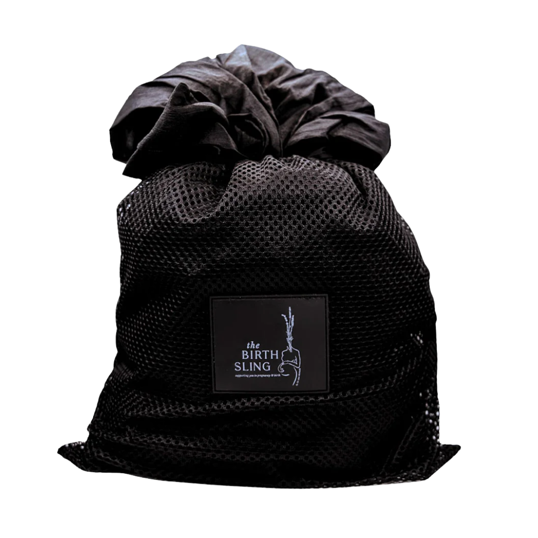 Black mesh bag labeled 'the BIRTH SLING' with fabric and clothing inside.
