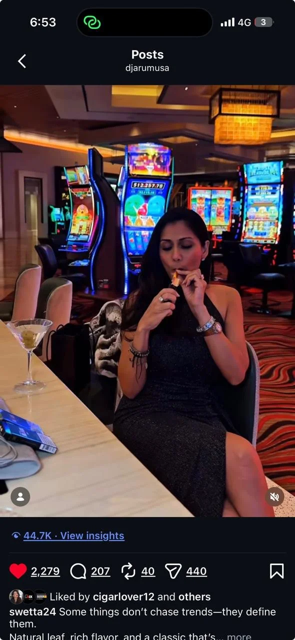 A woman in a black dress seated at a table in a casino, eating a snack. Slot machines with colorful lights are visible in the background.