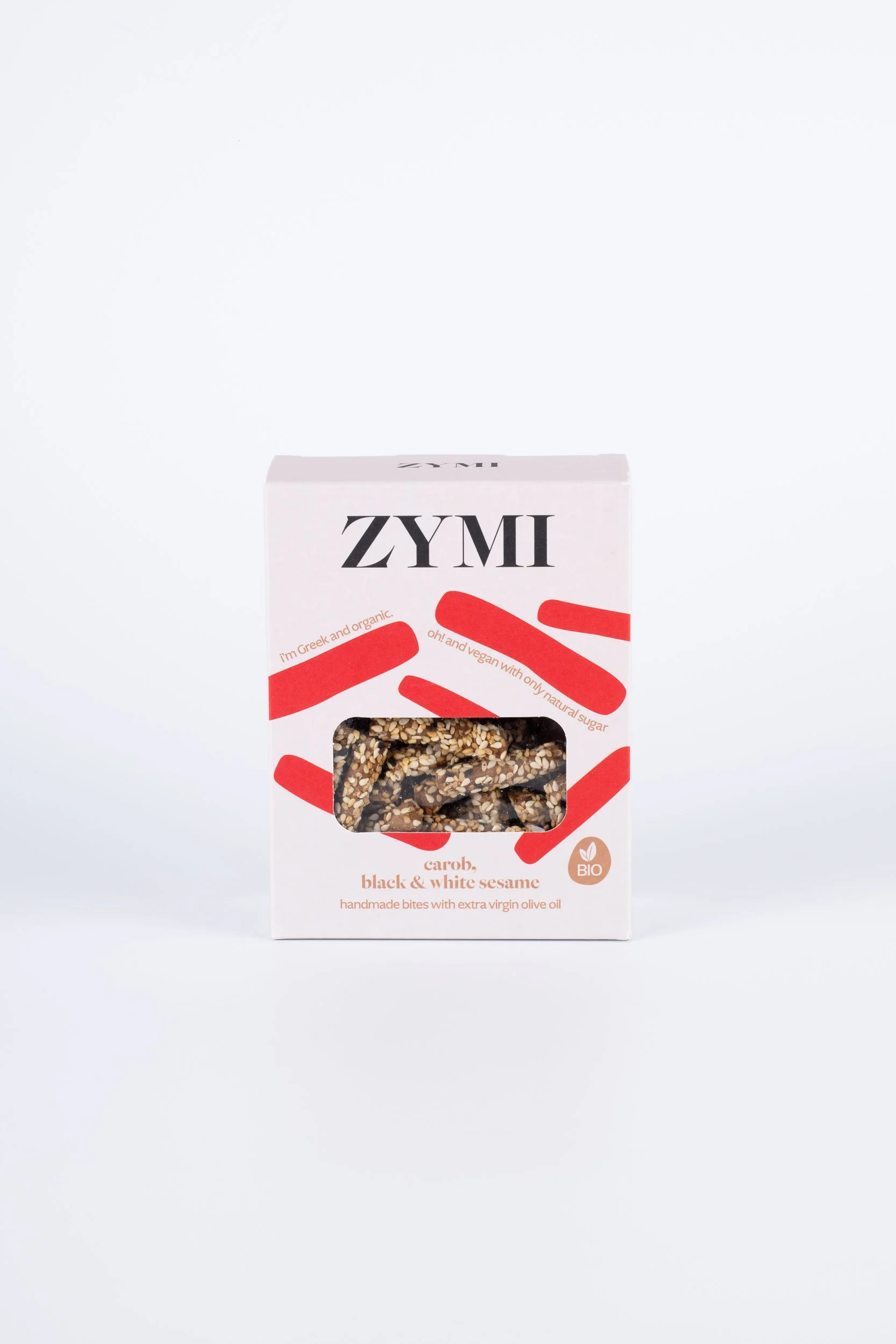 ZYMI product box in light colour with red details, showing carob, black & white sesame bites through a window cutout.