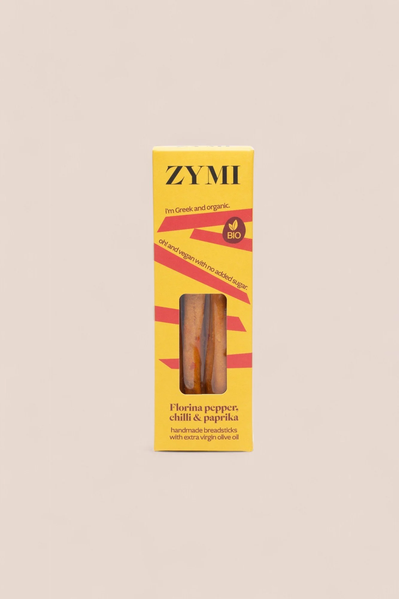 ZYMI product box in bright yellow colour with red lines, showing florina pepper, chili & paprika breadsticks through a window cutout.