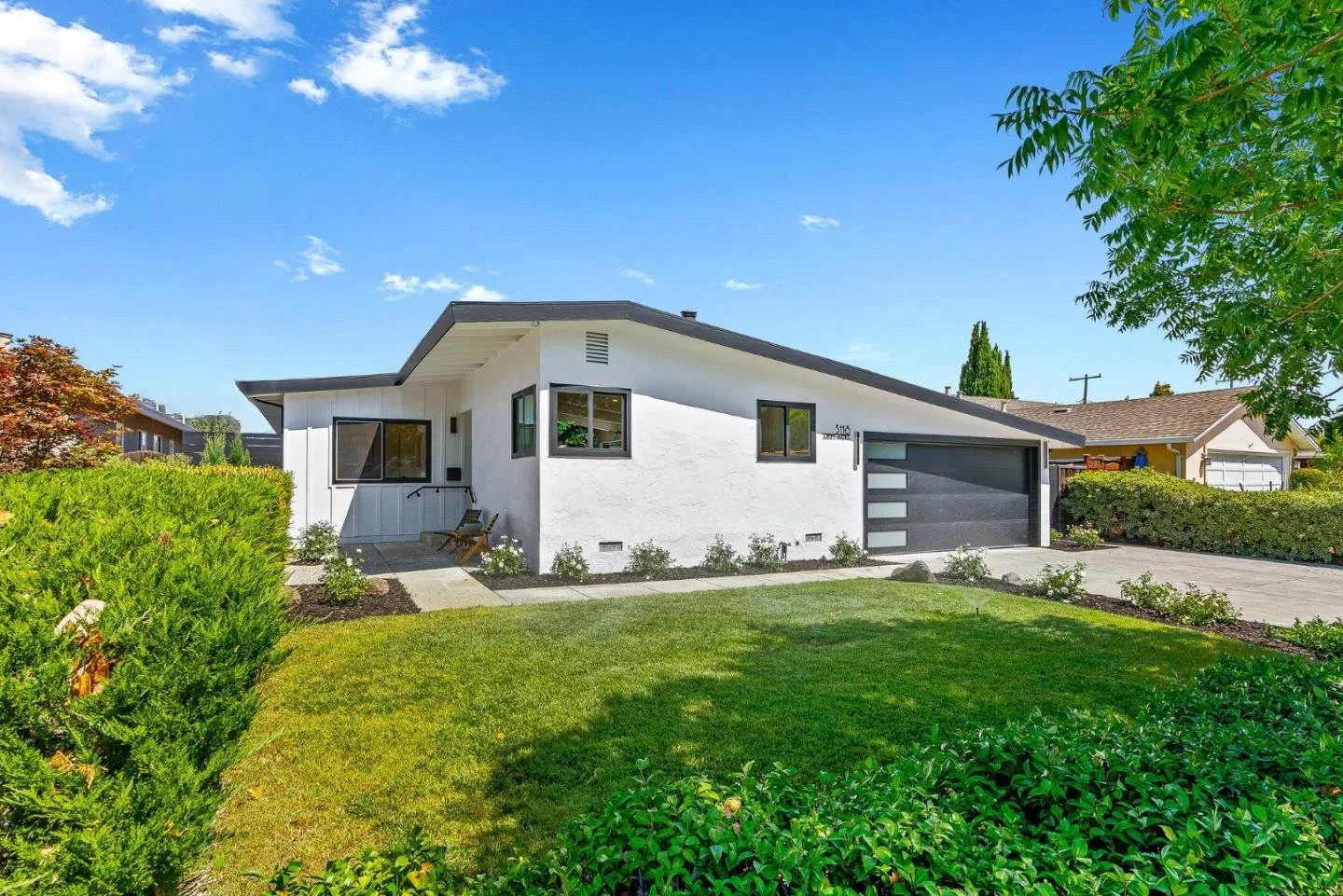 Front view of a gray suburban house with a manicured garden