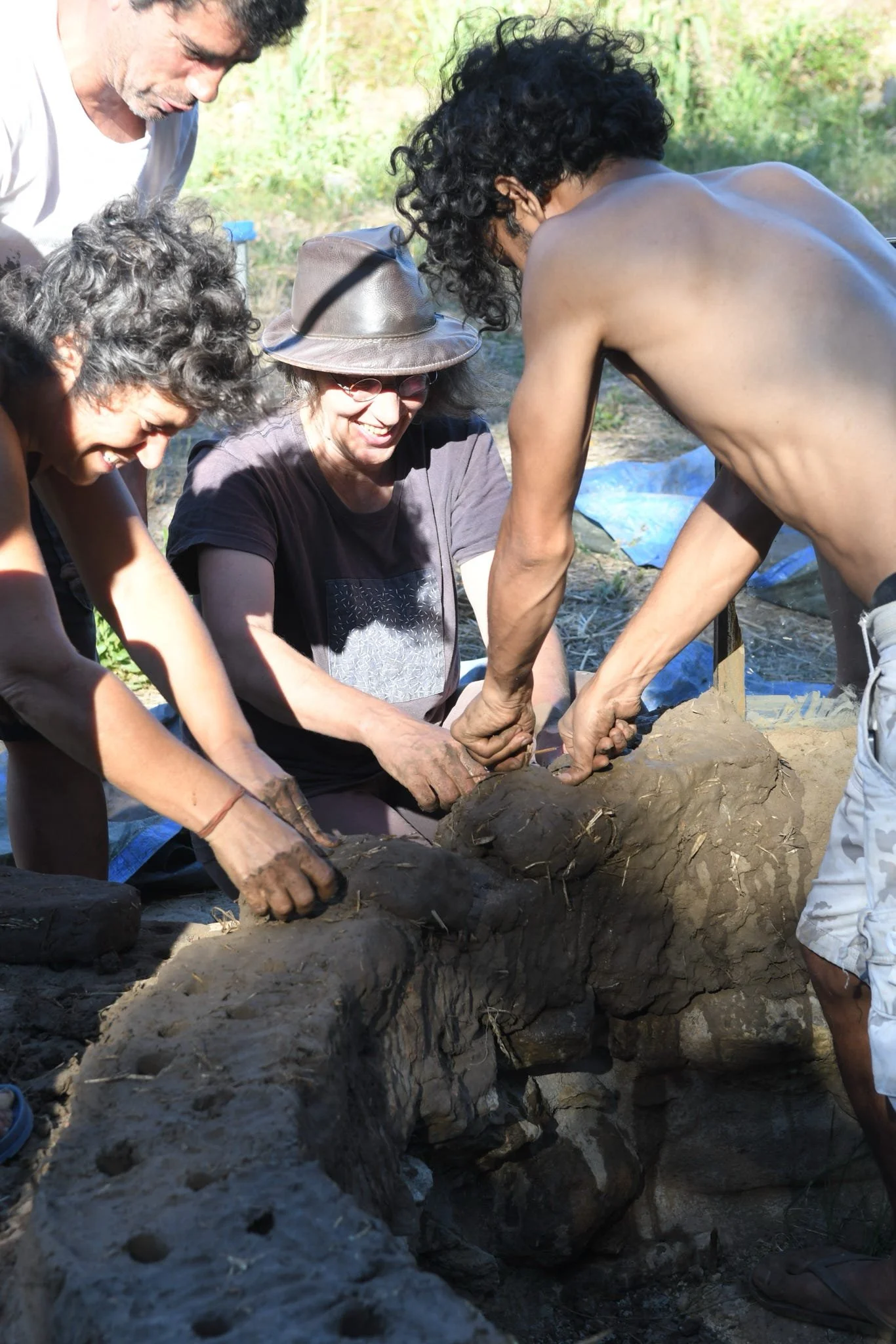 A group of people are working together outdoors, digging in the dirt and handling a large, early-stage dinosaur fossil.