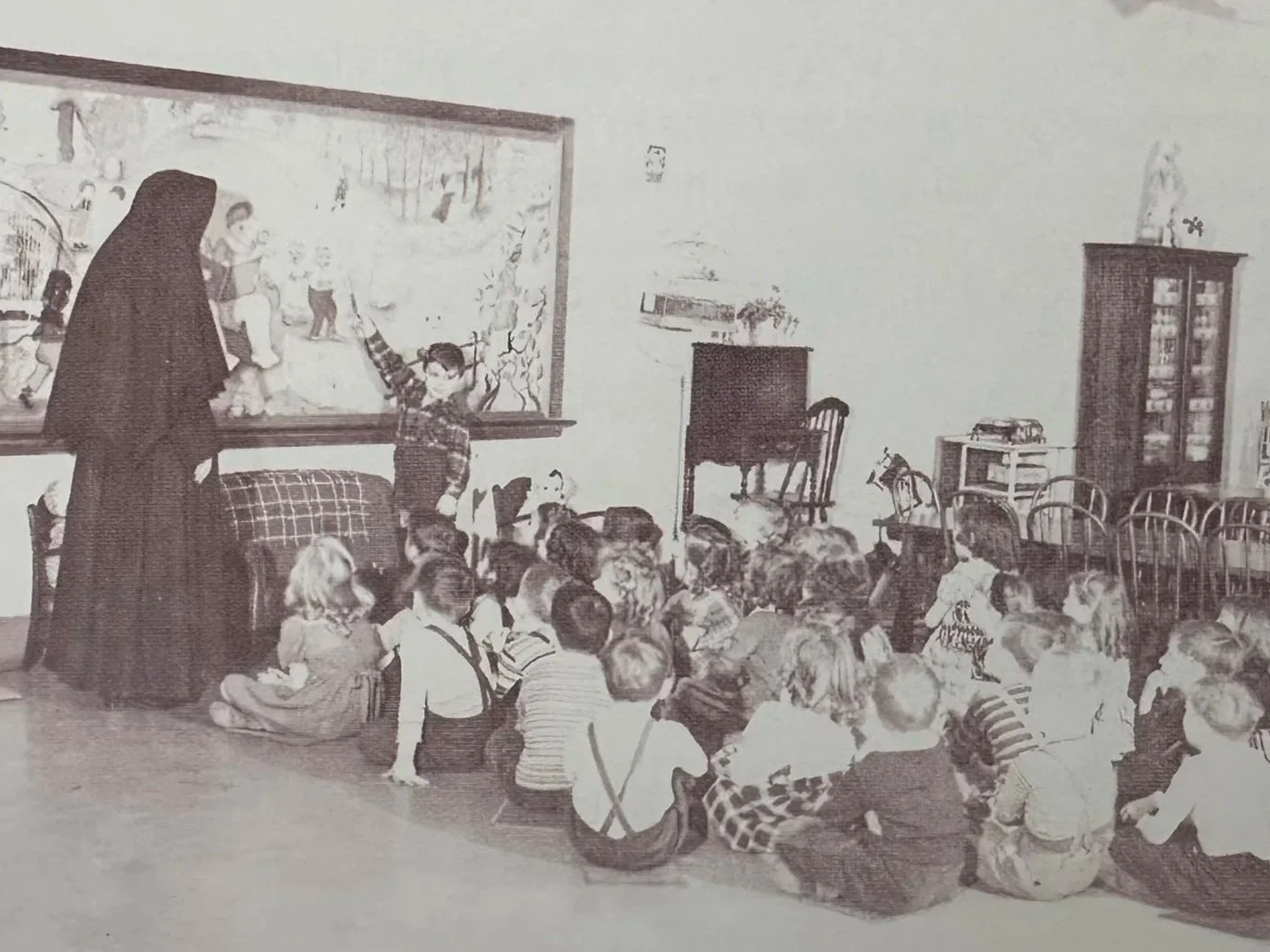 An image of a religious sister teaching children in the early 20th century